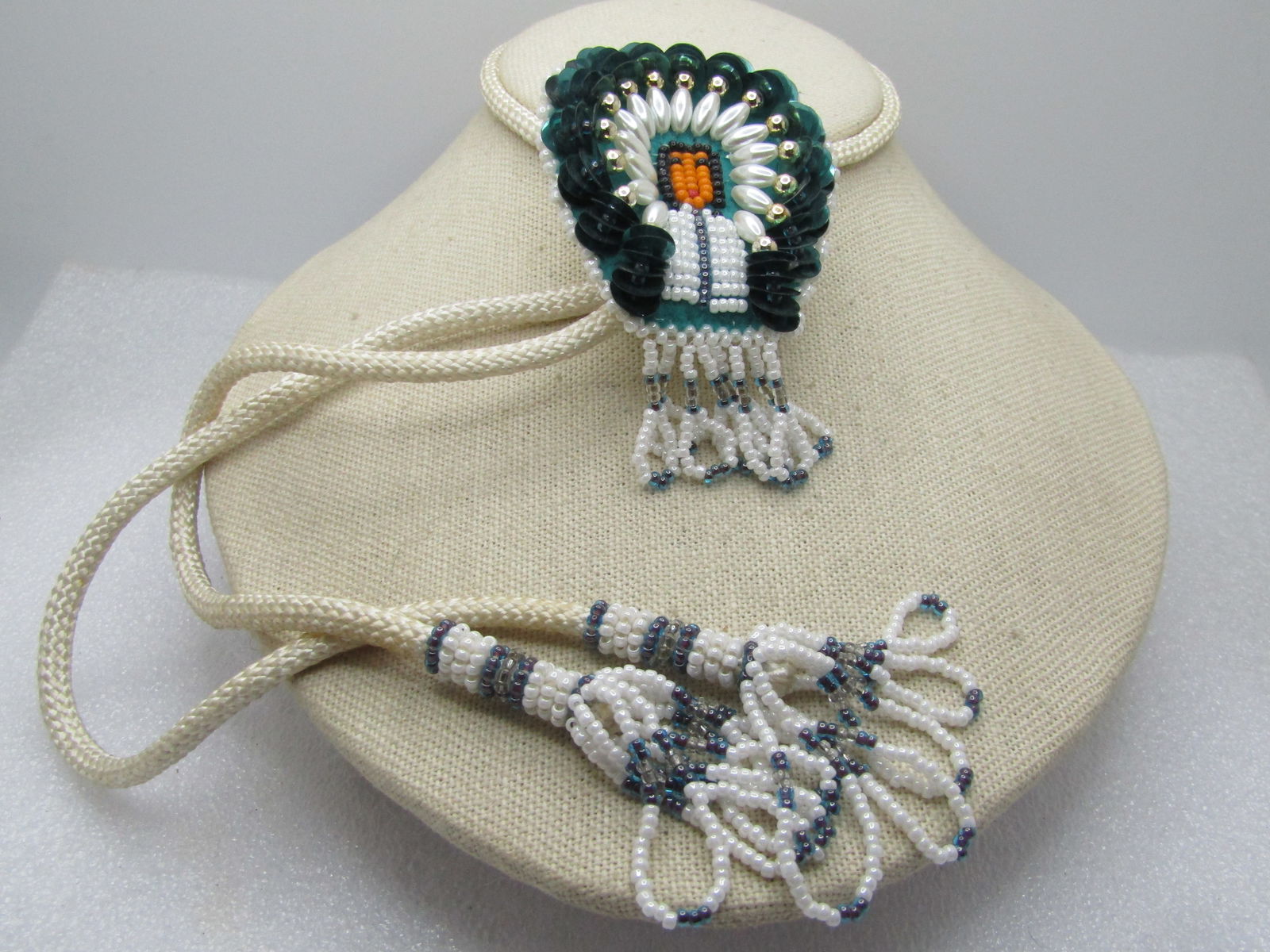 Vintage Beaded/Sequins Chief Bolo Tie, White/Green/Gray, 34" with Tassels, 1970's-1980's: Vintage Beaded/Sequins Chief Bolo Tie, White/Green/Gray, 34" with Tassels, 1970's-1980's. This has a glass seed beaded Native American Chief with large dark green sequin headdress and faux pearls and