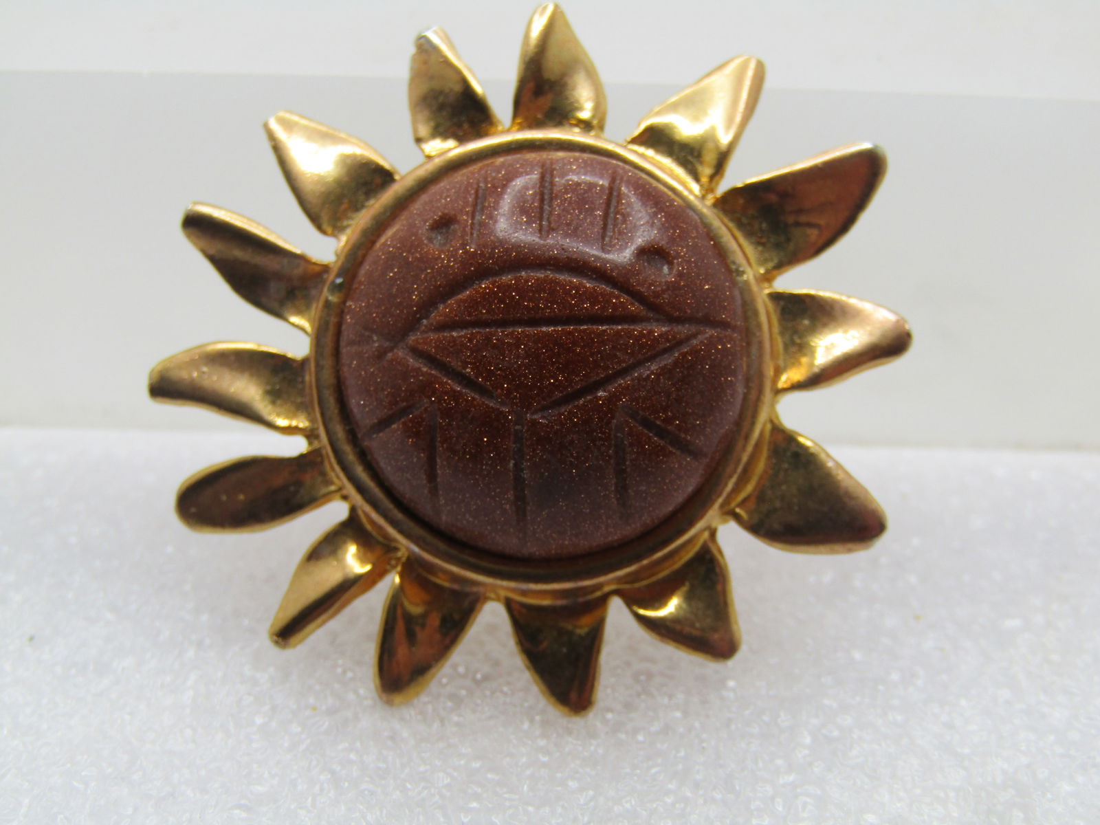 Vintage Carved Goldstone Sun Brooch, , 1970's-1980's.: Vintage Carved Goldstone Sun Brooch, , 1970's-1980's. Gold tone setting and rays with a center with an appx. 20mm carved domed round gold stne. It is appx. 1.5" wide. Locking clasp. It is not signed b
