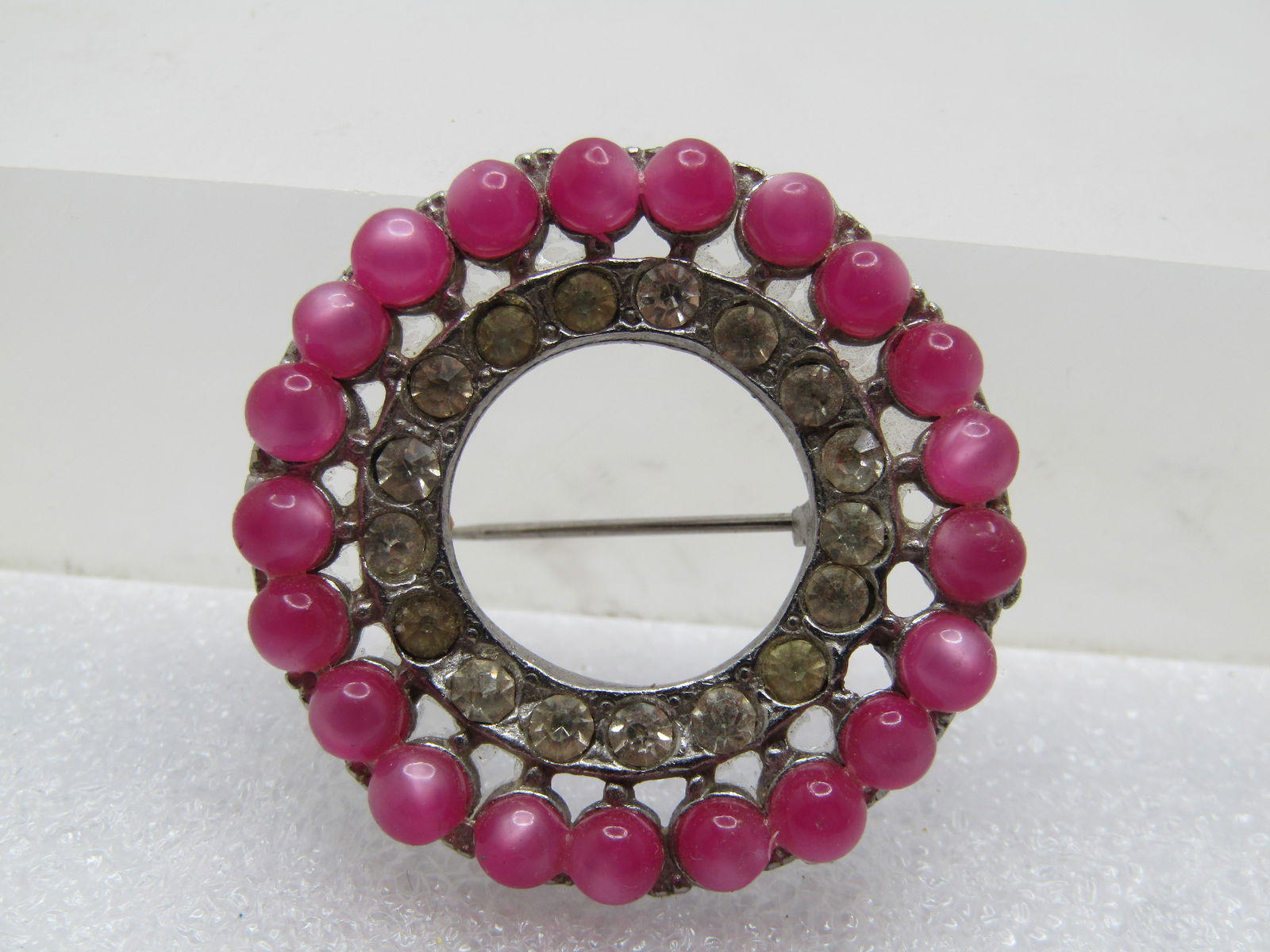 Vintage Pink Moonglow & Clear Rhinestone Brooch, Circle, 1940's-1950's: Vintage Pink Moonglow & Clear Rhinestone Brooch, Circle, 1940's-1950's. Silver tone cast metal with locking clasp. Center is open with a frame of clear rhinestones that sit lower than the pink
