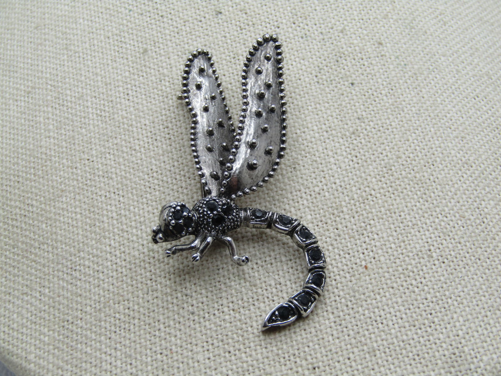 Vintage Dragonfly Brooch, Black Glass Stones, 1980's: Vintage Dragonfly Brooch, Black Glass Stones, 1980's. It has a textured finish with a darker washed look to it. The bod is coiled and there are black stones in the head, torso and long tail. The wings