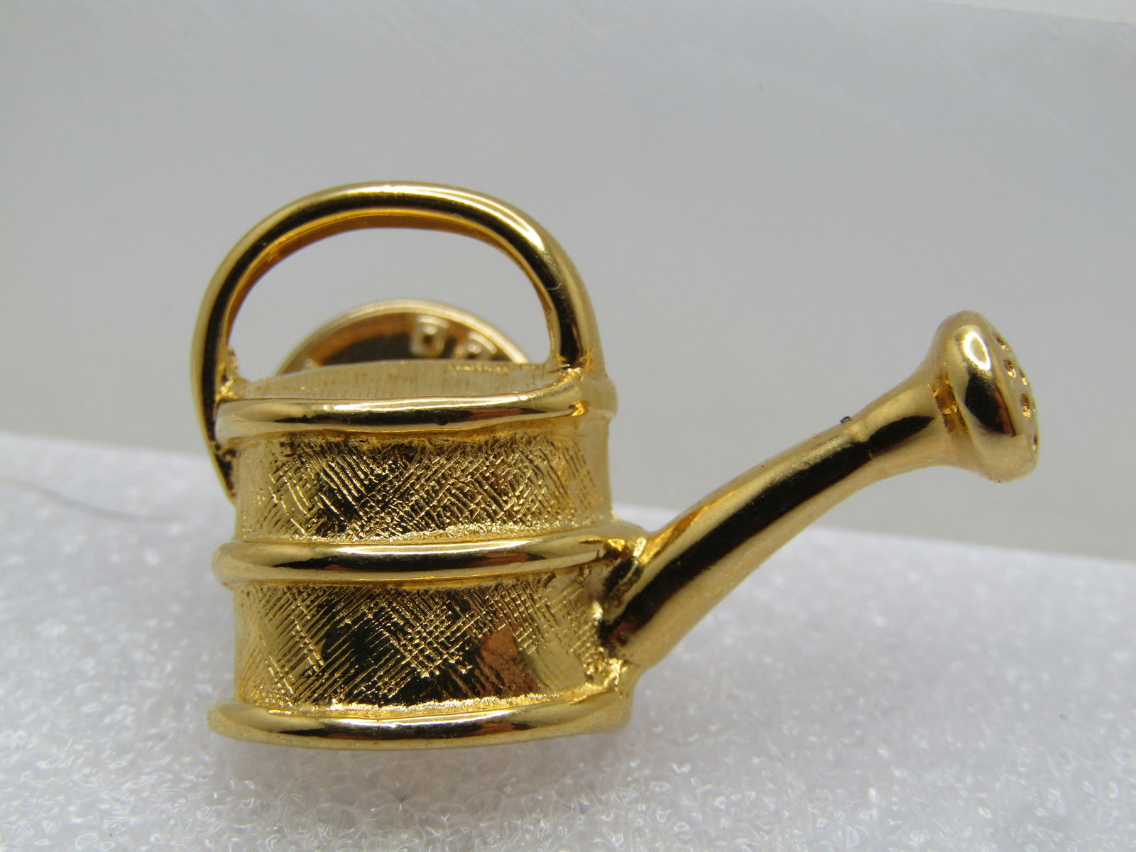 Vintage Watering Can Tack Pin, Signed Trifari, 1960's-1970's: Vintage Watering Can Tack Pin, Signed Trifari, 1960's-1970's. Gold tone with textured can and smooth handle and spout. It is 3/4" tall and 1.25" wide. Very clean and very good condition. (W31624.5