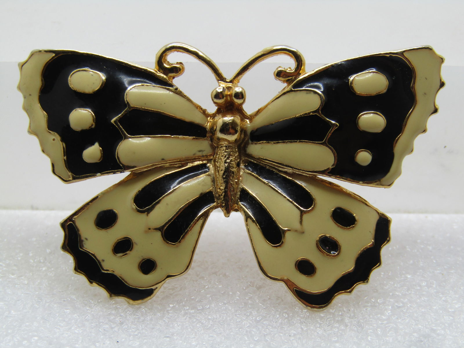 Vintage Enameled Butterfly Brooch, Black/Off-White, 1960's: Vintage Enameled Butterfly Brooch, Black/Off-White, 1960's. It is appx. 2.25" wide and 1.25" tall. Gold tone with flooded enameling set with raised gold tone detail, torso/body. Locking clasp. It is n