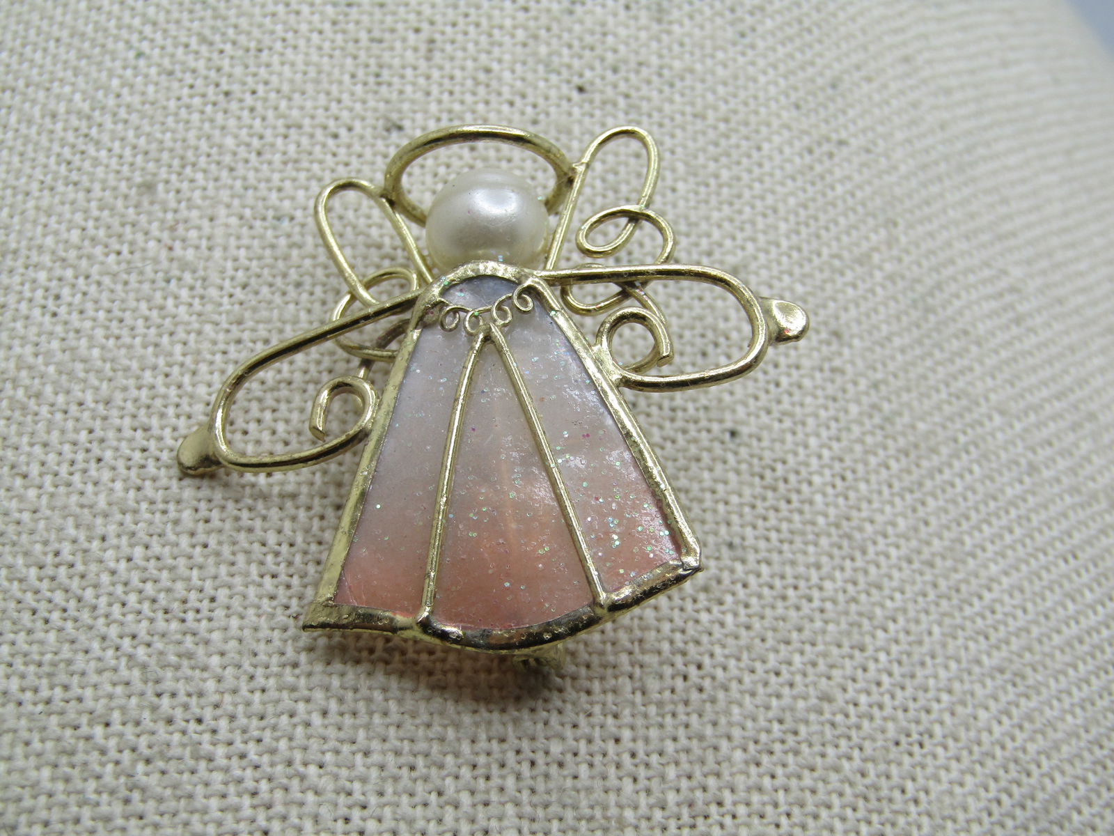 Vintage Scrolled Shell Angel Brooch, Faux Pearl, 1980's: Vintage Scrolled Shell Angel Brooch, Faux Pearl, 1980's. Pale cream to pink triangular shell frame in gold tone edging with scrolled wire arms and wings and halo with a 10mm white faux pearl head. 