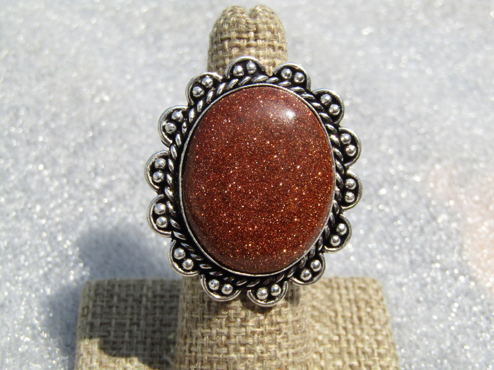 Southwestern Themed Sunstone Ring, Sz. 8, 1990's-2000's: Southwestern Themed Sunstone Ring, Sz. 8, 1990's-2000's. Silver tone ring with a scalloped edge wider than the stone with rope accent at the base of the bezel. The stone is an oval sunstone that is ap