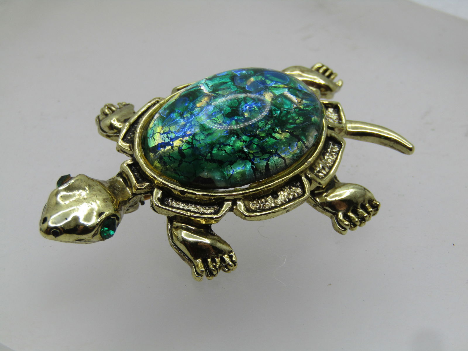 Vintage Green/Blue Foiled Turtle Brooch, 1960's: Vintage Green/Blue Foiled Turtle Brooch, 1960's. This turle hs a fancy teal/green/blue foiled cabochon back for a shelel with green rhinestone eyes. It is gold tone and appx.2-1/8" long and 1.25"