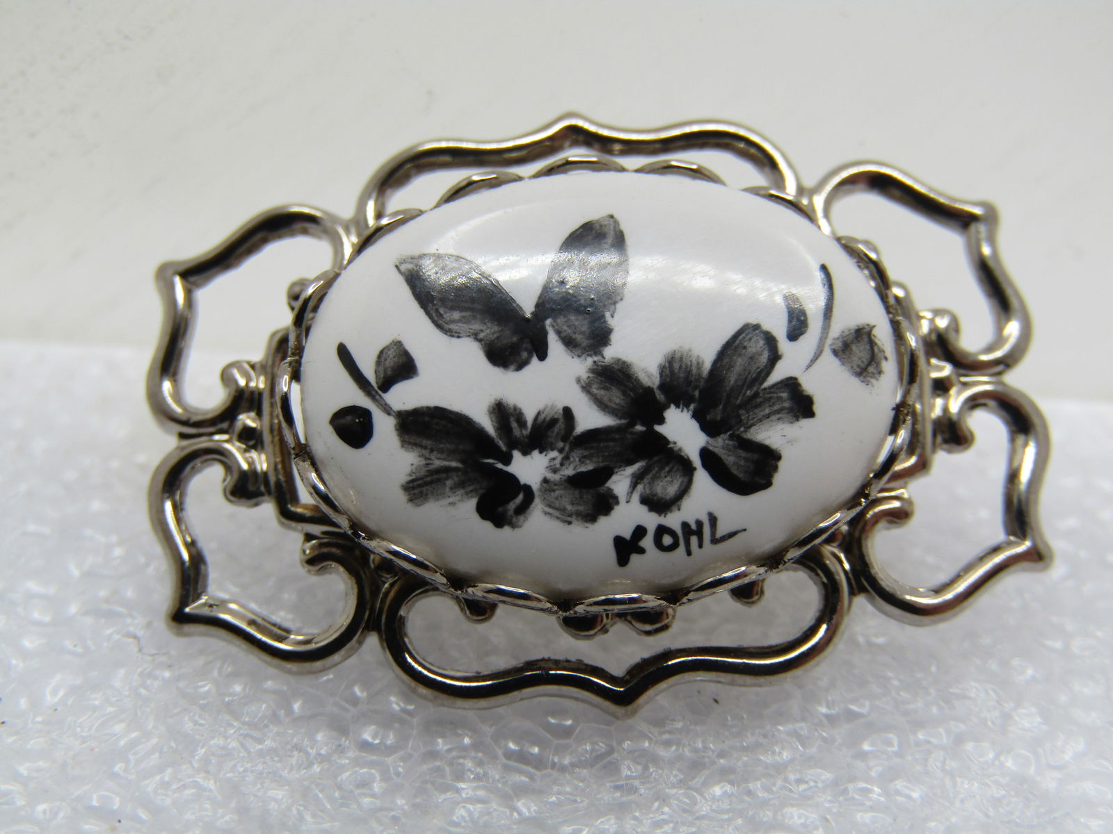 Vintage Hand Painted Butterfly Brooch, Signed Kohl, 1960's-1970's: Vintage Hand Painted Butterfly Brooch, Signed Kohl, 1960's-1970's. Silver tone open frame with a bezel around a ceramic white stone that is appx. 3/4" by 1/2" and charcoal butterflies and flowers