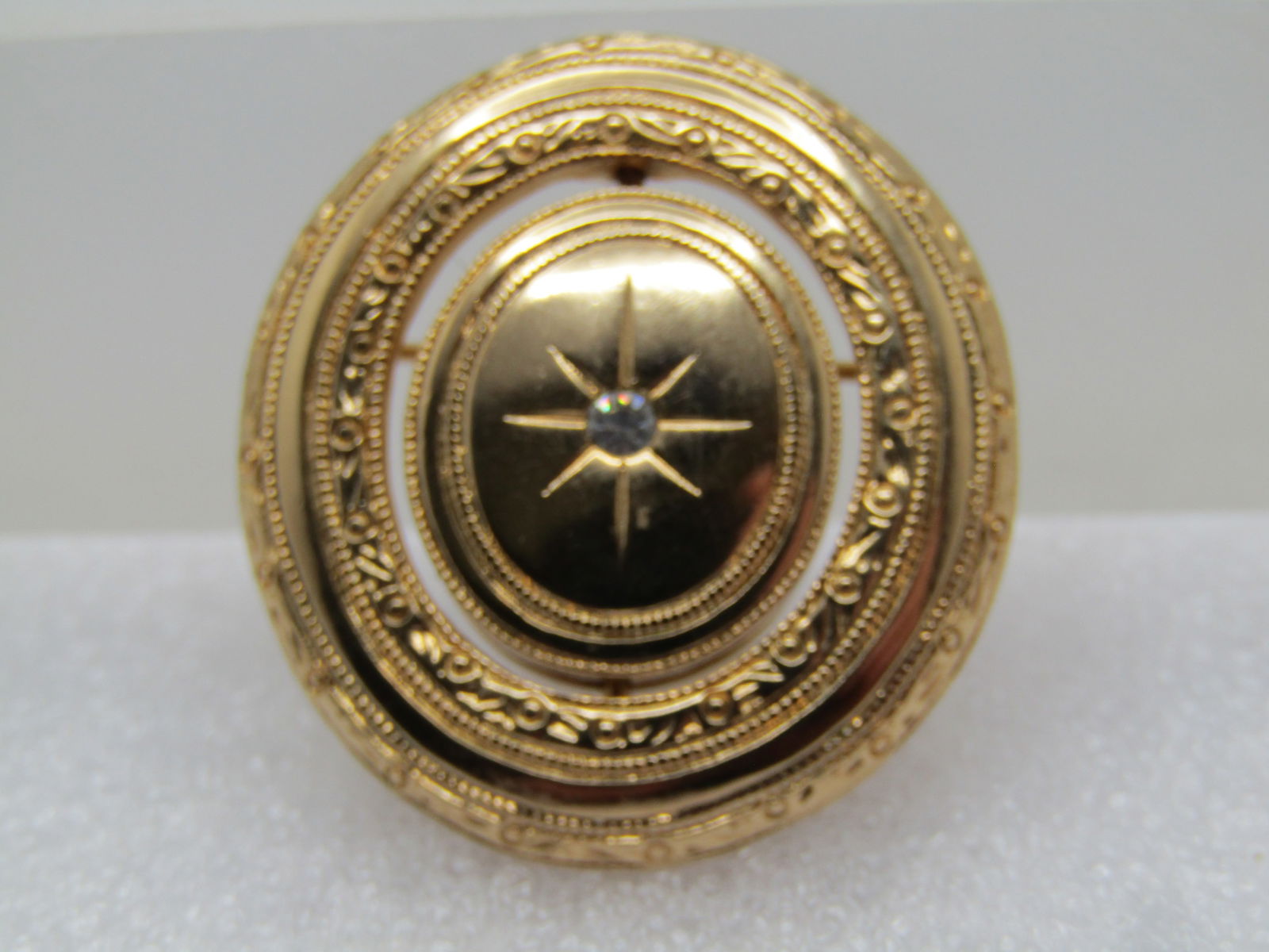 Vintage Avon Photo Locket Spinner Brooch, 1970's-1980's: Vintage Avon Photo Locket Spinner Brooch, 1970's-1980's. Gold tone brooch that is papx. 1-1/3" tall and 1-1/8" wide. The center has an oval that will spin (when the pinback is open) so you can have th