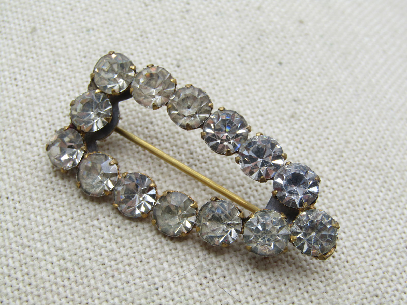 Antique Clear Rhinestone Pointed Brooch C-Clasp 1920's.: Antique Clear Rhinestone Pointed Brooch C-Clasp 1920's, gold tone with clear 6mm rhinestones. Open center brooch, pointed on one end. 1.75" long by 7/8" wide. It is not signed or marked. The stones