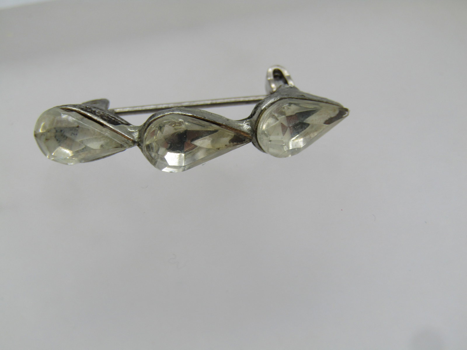 Vintage Triple Pear Rhinestone Brooch, 1940's: Vintage Triple Pear Rhinestone Brooch, 1940's. Silver tone cast metal. each stone is clear and appx. 10mm by 6mm. The stones are set in a slightly curved design with them stack end to end. Locking cla