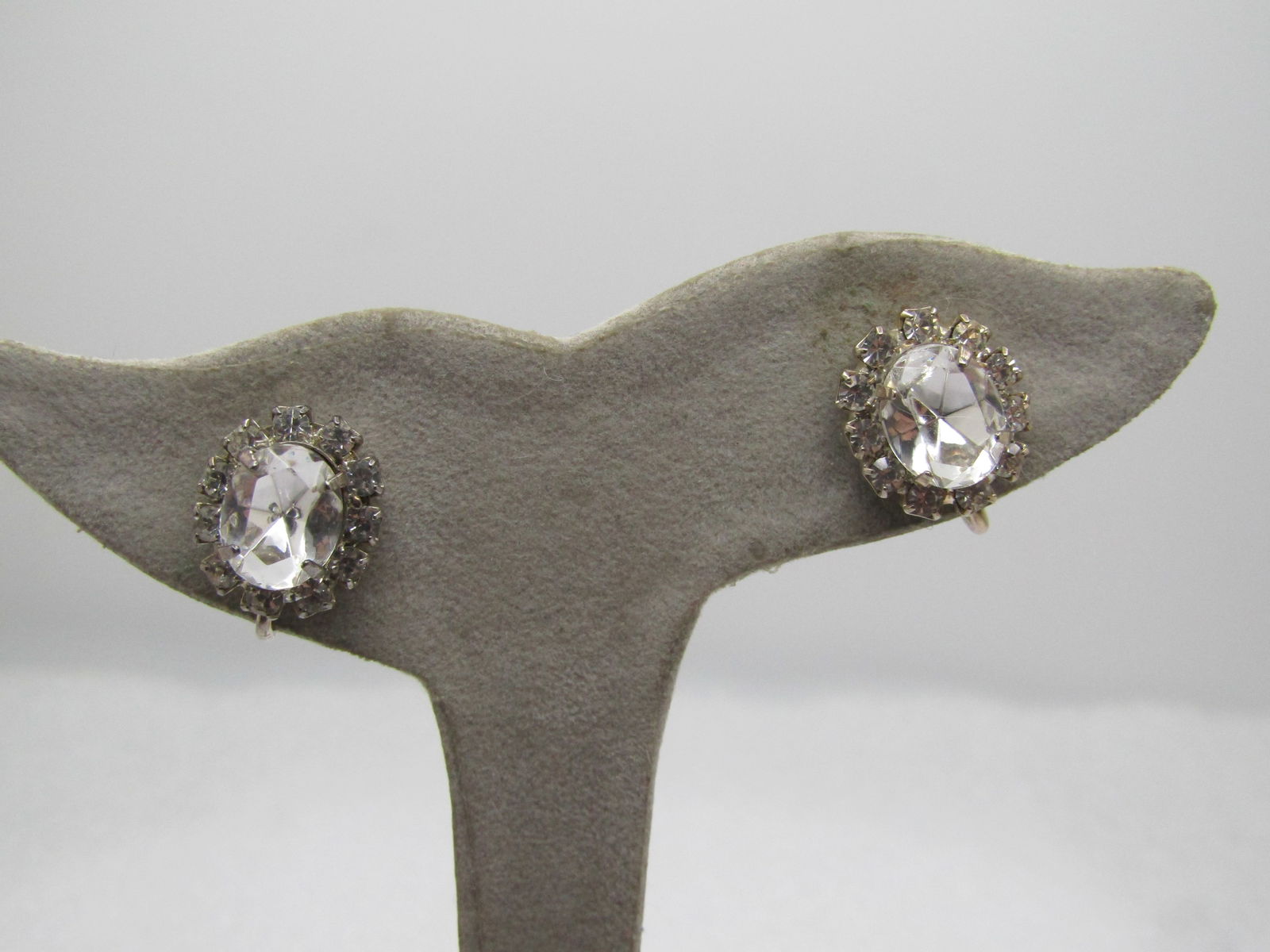 Vintage Clear Rhinestone Cluster Earrings, Clip, 1960.: Vintage Clear Rhinestone Cluster Earrings, Clip, 1960. Silver tone 10mm by 8mm oval center stone with clear 2.5mm rhinestone halo. The earrings are appx. 5/8" tall by 1/2" wide. They are not marked or