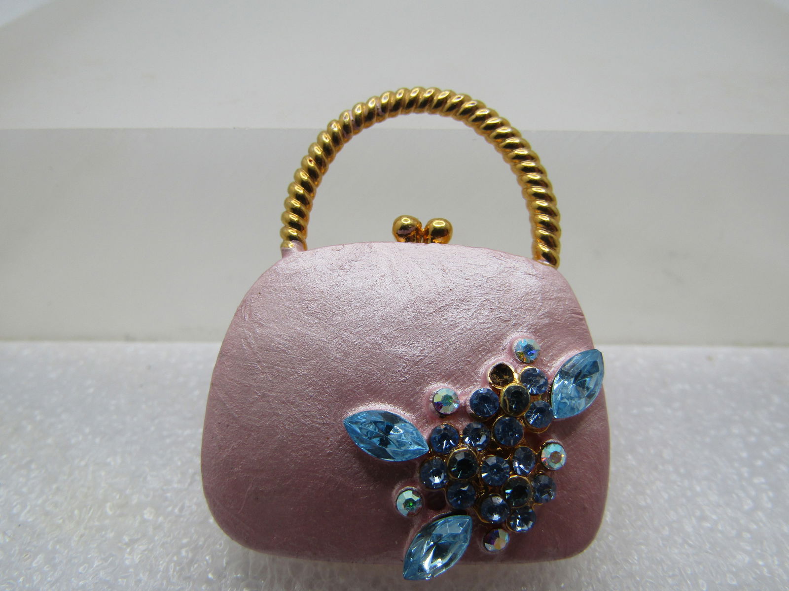 Vintage Pink Pearly Purse Tack Pin, Blue Rhinestones, 1980's: Vintage Pink Pearly Purse Tack Pin, Blue Rhinestones, 1980's. Gold tone handle and snap on the purse with a pearly pink enameled purse and aqua and auroral borealis smaller stones. One stone was