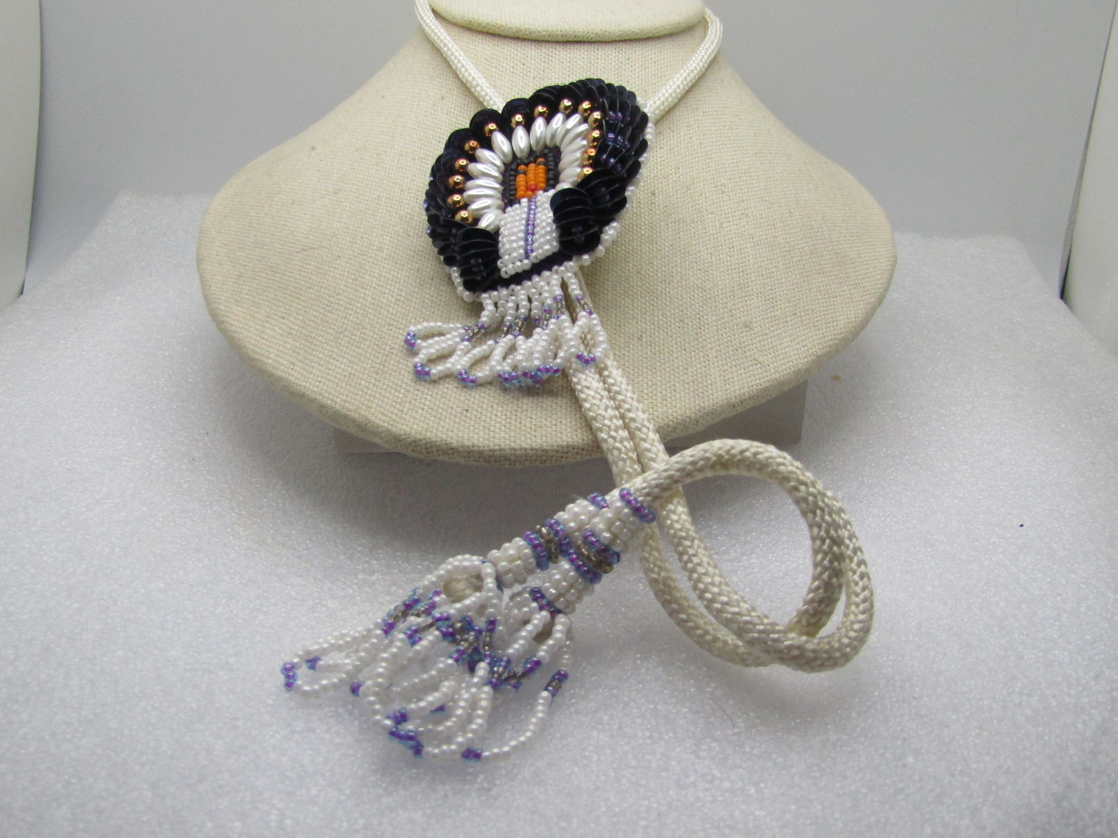 Vintage Beaded/Sequins Chief Bolo Tie, White/Purple/Gray, 34" with Tassels, 1970's-1980's: Vintage Beaded/Sequins Chief Bolo Tie, White/Purple/Gray, 34" with Tassels, 1970's-1980's. This has a glass seed beaded Native American Chief with black sequin headdress and faux pearls and gold