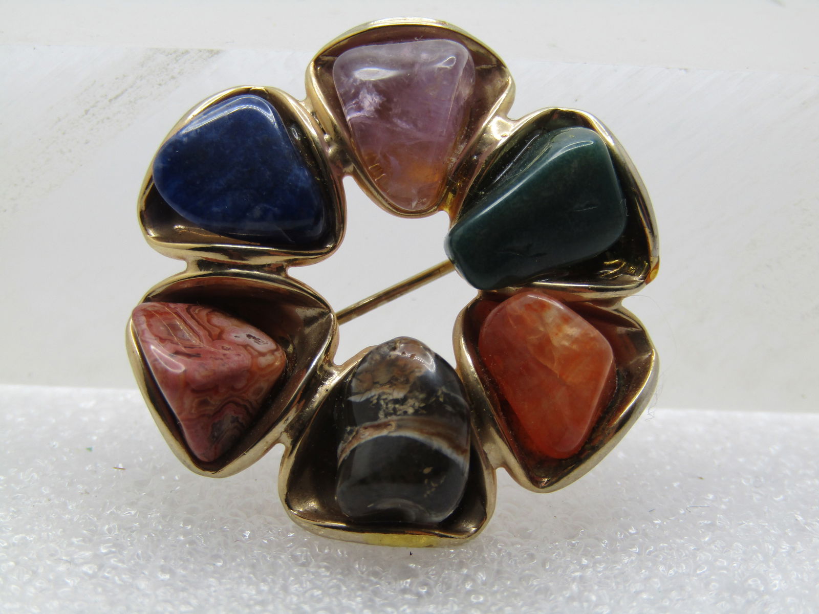 Vintage Polished Agate Brooch, 1960's-1970's: Vintage Polished Agate Brooch, 1960's-1970's. Gold tone sircle brooch with size stones set in triangular dish-like settings. Sodalite, pink quartz; moss agate and three other stones. The stones