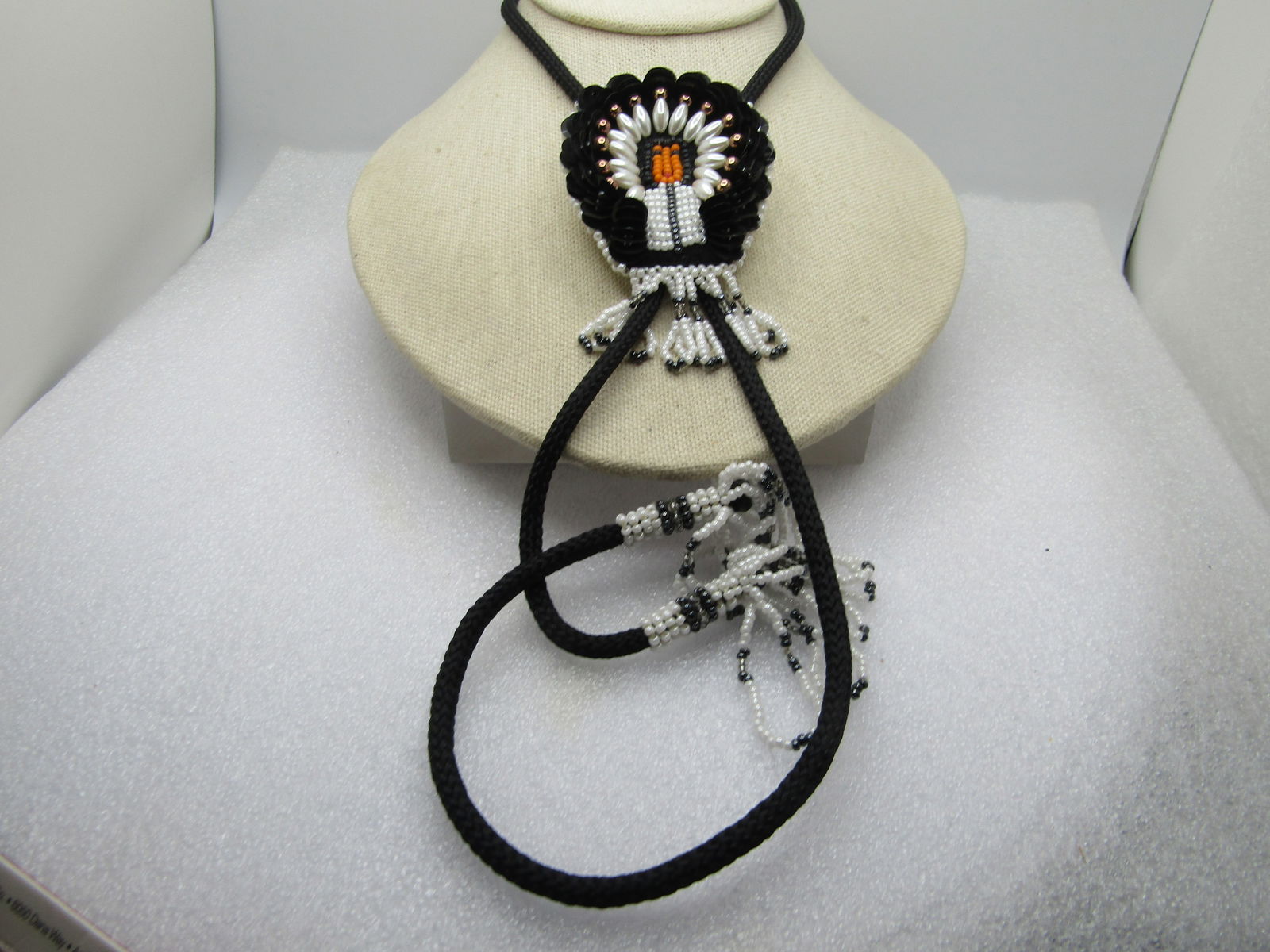 Vintage Beaded/Sequins Chief Bolo Tie, White/Black/Gray, 36" with Tassels, 1970's-1980's: Vintage Beaded/Sequins Chief Bolo Tie, White/Black/Gray, 36" with Tassels, 1970's-1980's. This has a glass seed beaded Native American Chief with black sequin headdress and faux pearls and gold tone b