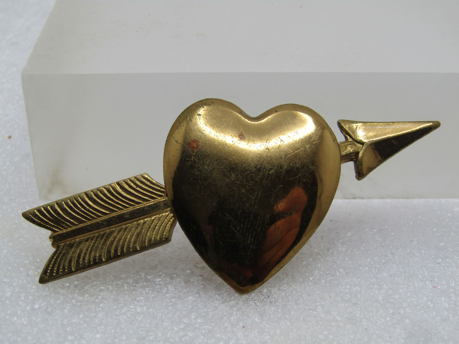 Vintage Heart and Arrow Brooch, C-Clasp, 1940's-1950's: Vintage Heart and Arrow Brooch, C-Clasp, 1940's-1950's. Gold tone pressed metal brooch that is appx. 2.5" wide and 1.25" tall. The heart in the center is domed. Very good vintage condition. It is not