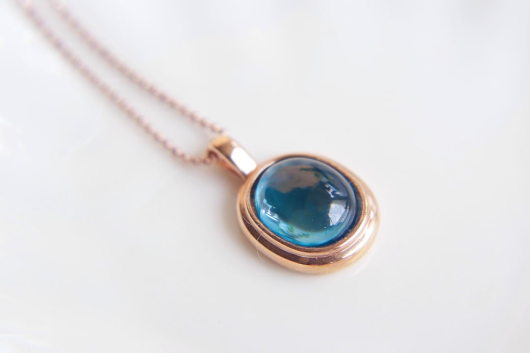 18K gold pendant set with topaz: Title: 18K gold pendant set with topaz Description: This pendant is a stunning piece of jewelry, set with vibrant topaz stones and luxurious 18K gold. Its simple yet elegant design makes it a