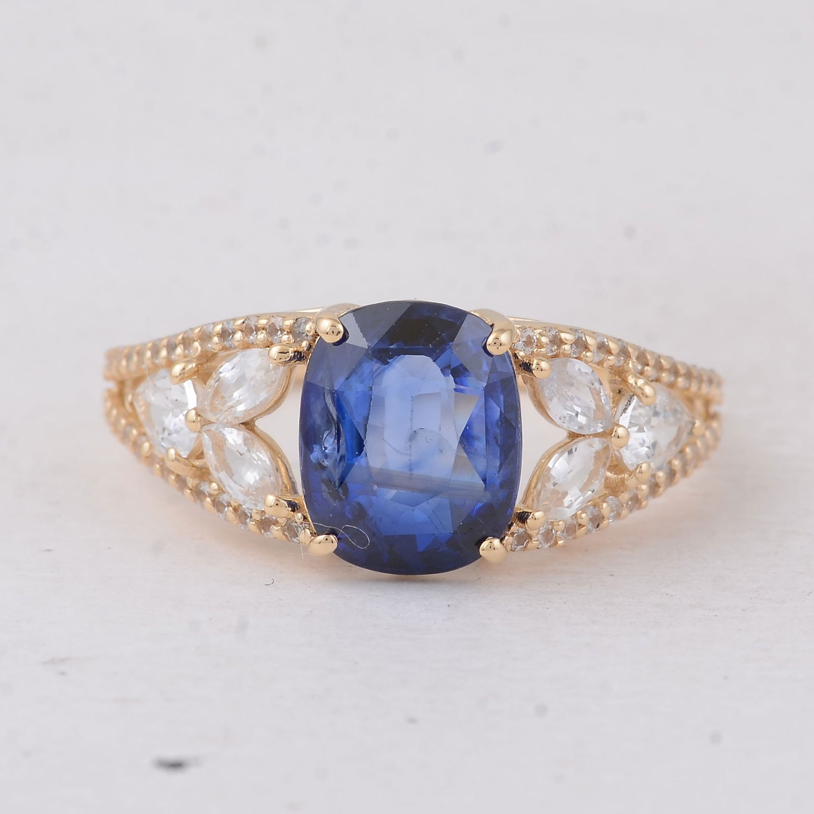 3.70 Ct Cushion Sapphire 9K Gold Ring: 3.70 Total Carat Sapphire 9K Gold Ring Specifications - Total Weight 2.491 g - Center Gemstone Sapphire - Gemstone Carat Weight 2.67 Carats - Gemstone Measurements 9X7.30X4 mm - Additional Gemstones W