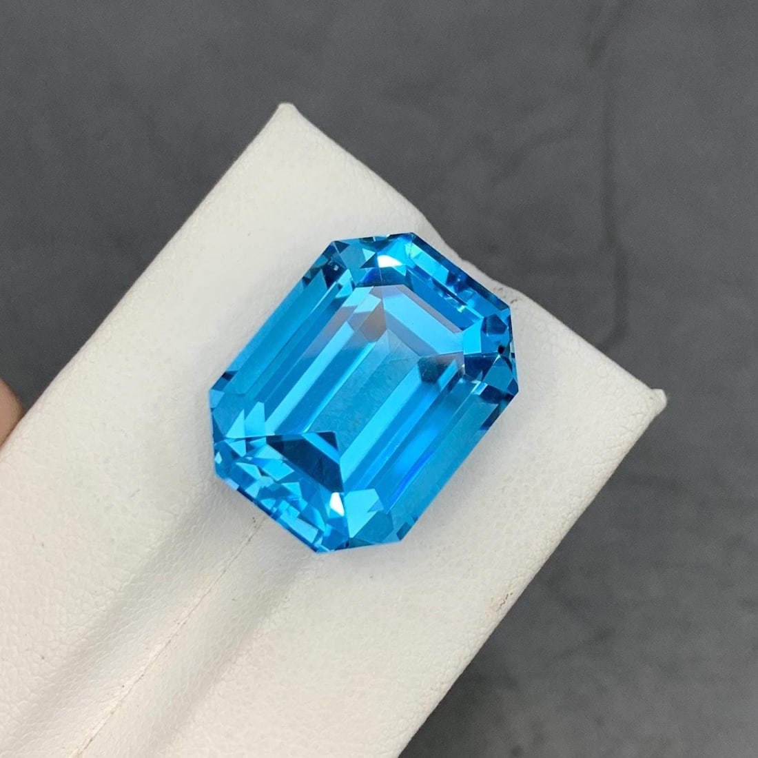 Emerald Cut Swiss Blue Topaz Gemstone: 35.40 Carat December Birthstone: Materials: Gemstone: Topaz Carat weight: 20.80 Swiss Blue Topaz gemstone. Expertly faceted in a classic emerald cut, this gem radiates a brilliant, vivid blue hue with exceptional clarity and light re