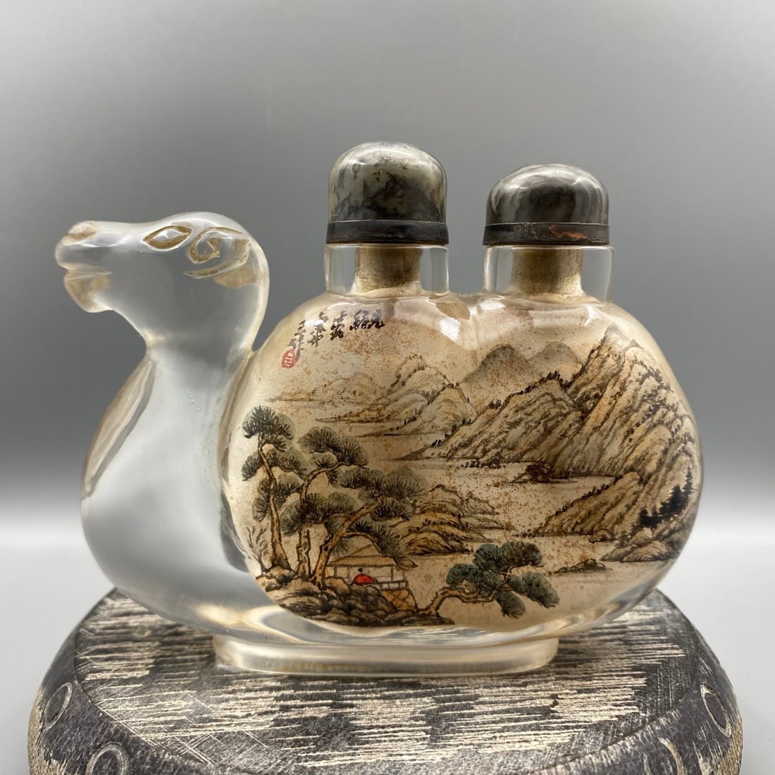 Peking Glass Inside Painting Mountain River Scene Design Snuff Bottle - Camel: Title: Peking Glass Inside Painting Mountain River Scene Design Snuff Bottle - Camel Origin: Chinese Date/Period: After1900 Materials: Peking Glass Dimensions: 110x90x30(mm) 4.33x3.54x1.18(inches)
