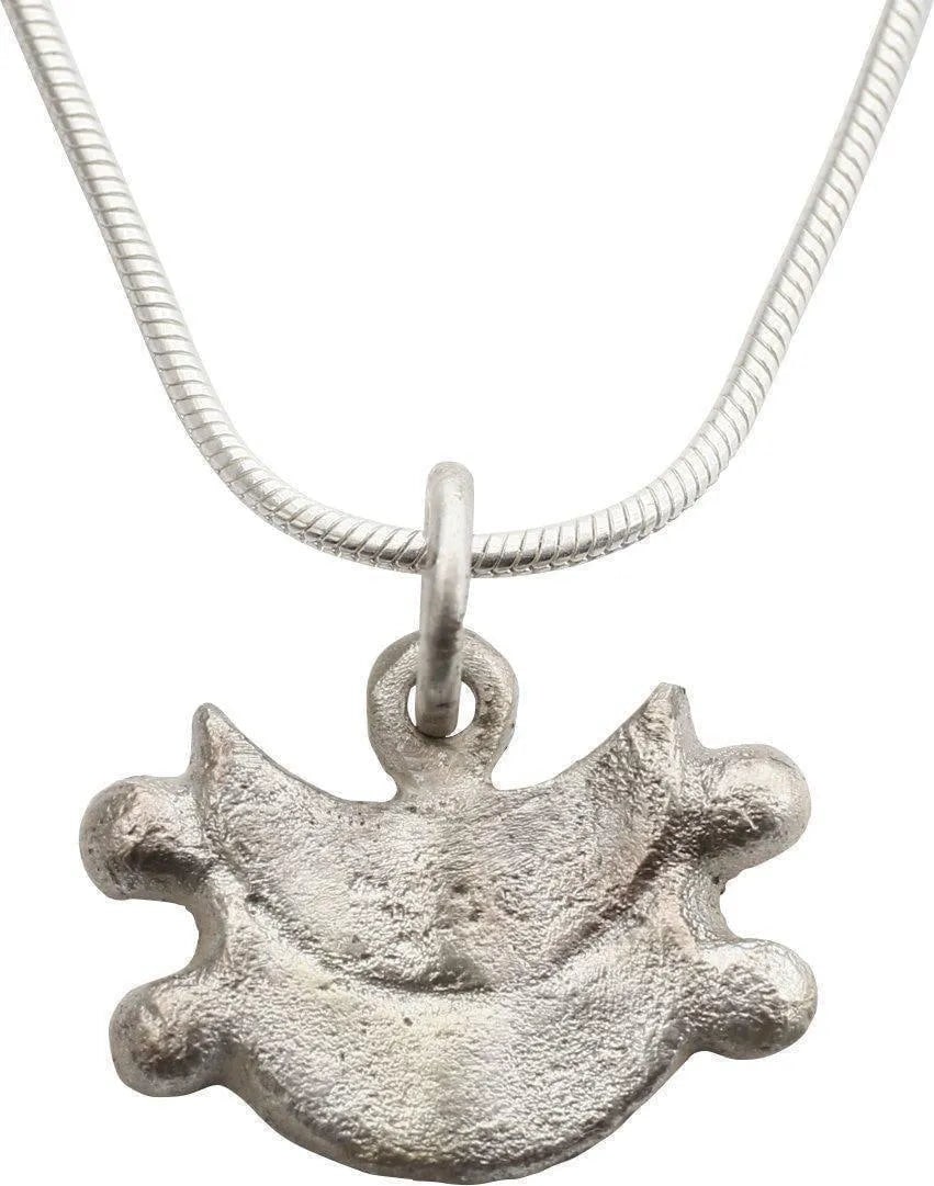 MEDIEVAL LADY'S NECKLACE PENDANT, C.1300-1500: Silvered bronze. Stylized shield shape in two horizontal crescents, undoubtedly a heraldic reference to the family history of fighting the Muslims in the Crusades and later. Just over 1/2" height.