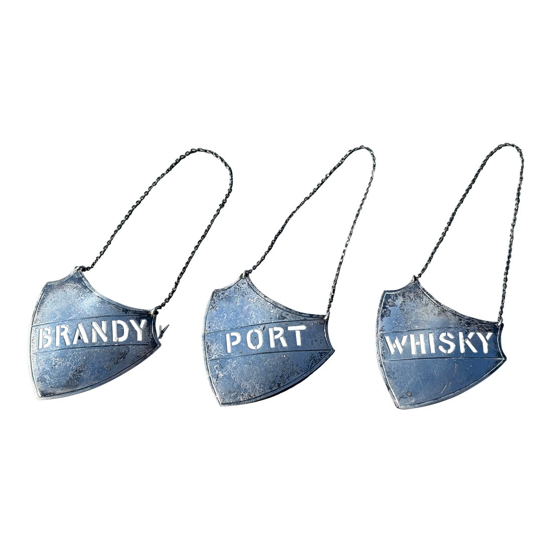 Late 19th C. Trio of Sterling Silver Liquor / Wine Decanter Plaques: Whiskey, Port, and Brandy. A trio of Late 19th. c. Sterling Silver Liguor / Wine Decanter Plaques. Shield Shaped with curvature and detail, suspended from a silver chain. 4.5" tall with full