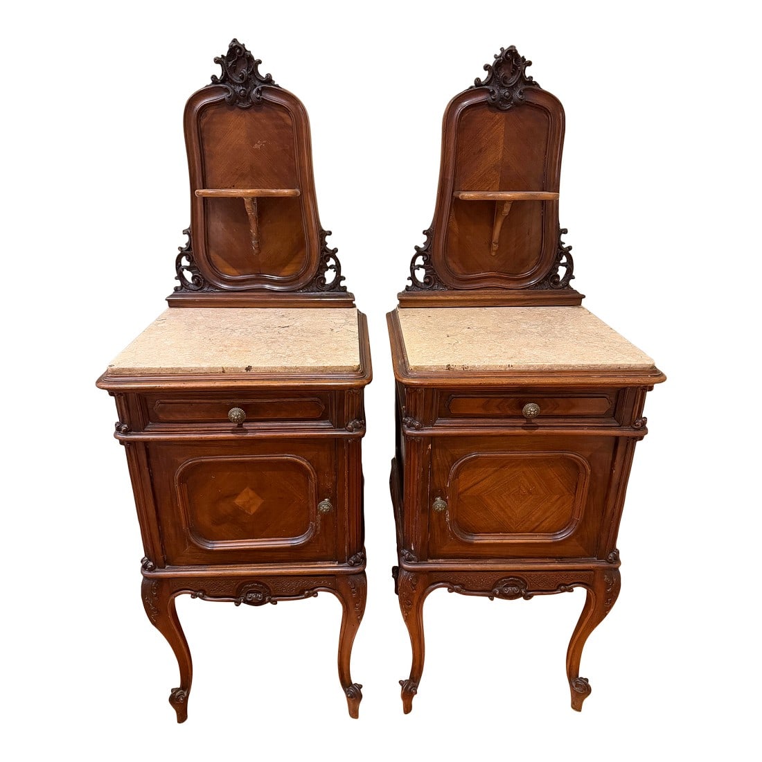 Pair of Antique French Marble-Top Bedside Cabinets / Nightstands With Carved Crests, Circa 1900: Elegant matched pair of antique French bedside cabinets featuring carved crest backs, marble tops, and cabriole legs. Each cabinet includes a small drawer above a paneled door with original hardware