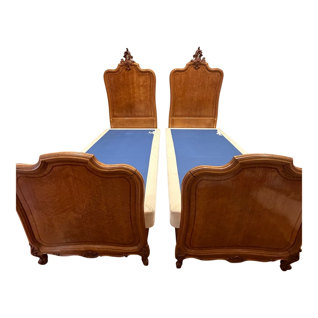 Pair of Antique French Twin Beds With Burl Wood Veneer & Hand-Carved Crests: This elegant pair of antique French twin beds showcases refined European craftsmanship, featuring richly figured burl wood veneer panels, softly serpentine silhouettes, and hand-carved crest details a