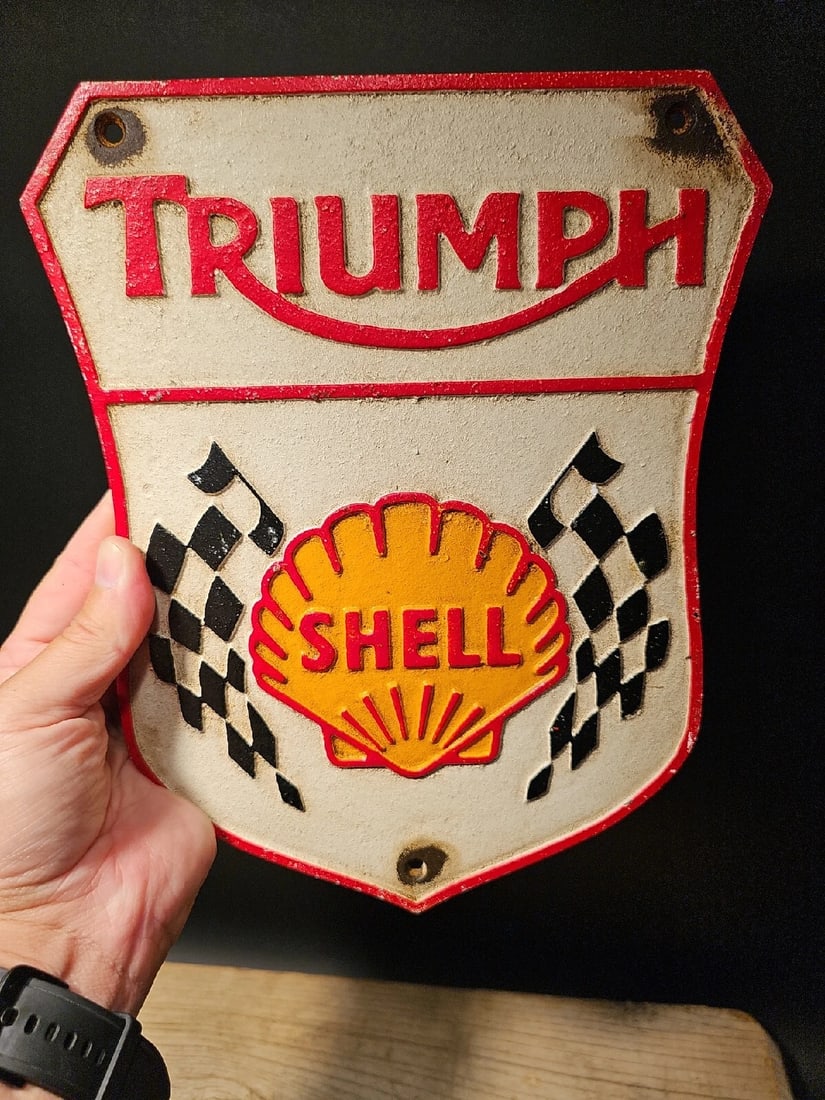 Cast Iron Triumph Shell Gas Oil Sign Plaque: Title:Cast Iron Triumph Shell Gas Oil Sign PlaqueDescription:8 3/4" Wide x 10 3/4" tall Introducing our extraordinary Reproduction Antique Style Cast Iron Triumph Shell Plaque. This magnificent piece