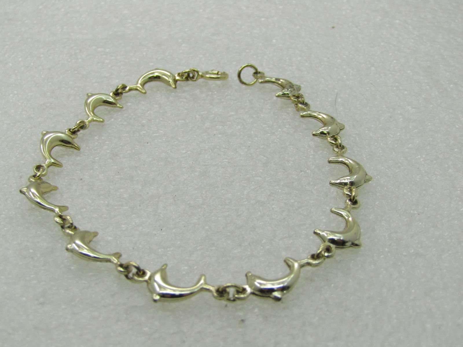 Gold Tone Dolphin Bracelet 7": Gold Tone Dolphin Link Bracelet 7". This is marked .925 on the spring clasp but I do not believe it is sterling under the gold. 11 arched dolphins conected by a ring link. Very good condition. Looks