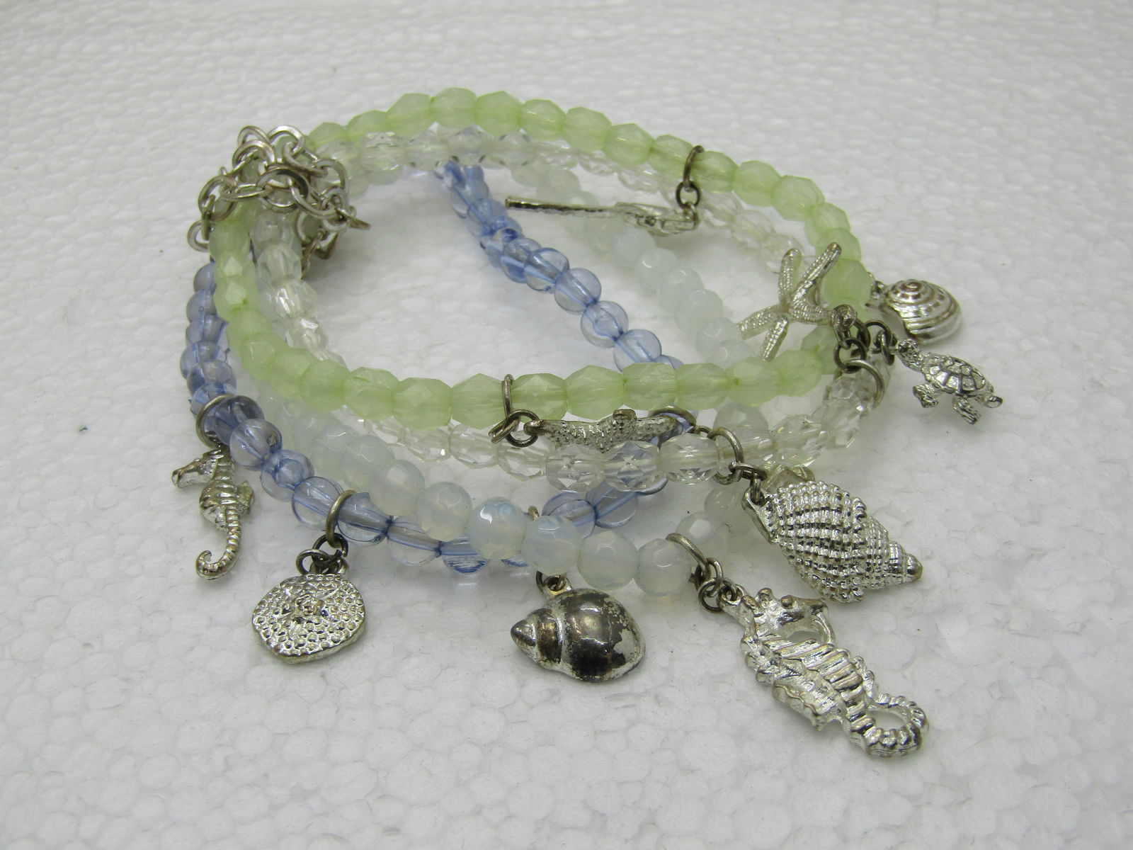 Four Seashell Beaded Stretch Bracelets, 6.5"-8" yellow/clear/white/lavender: Four Seashell Beaded Stretch Bracelets, 6.5"-8" yellow/clear/white/lavender faceted beads except the lavender are founded nad appx. 5.5mm. Silver tone charms, palm trees, star fish, sand dollar,
