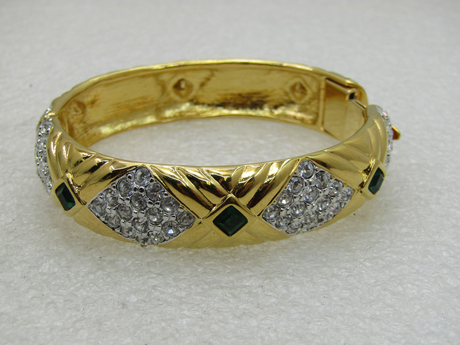 Nolan Miller Rhinestone Hinged Bracelet, 7.25", 5/8": Nolan Miller Rhinestone Hinged Bracelet, 7.25", 5/8". Pave clear stones set in diamond shaped silver tone patterns around the front of the bracelet with 4mm square deep sapphire blue colored stones