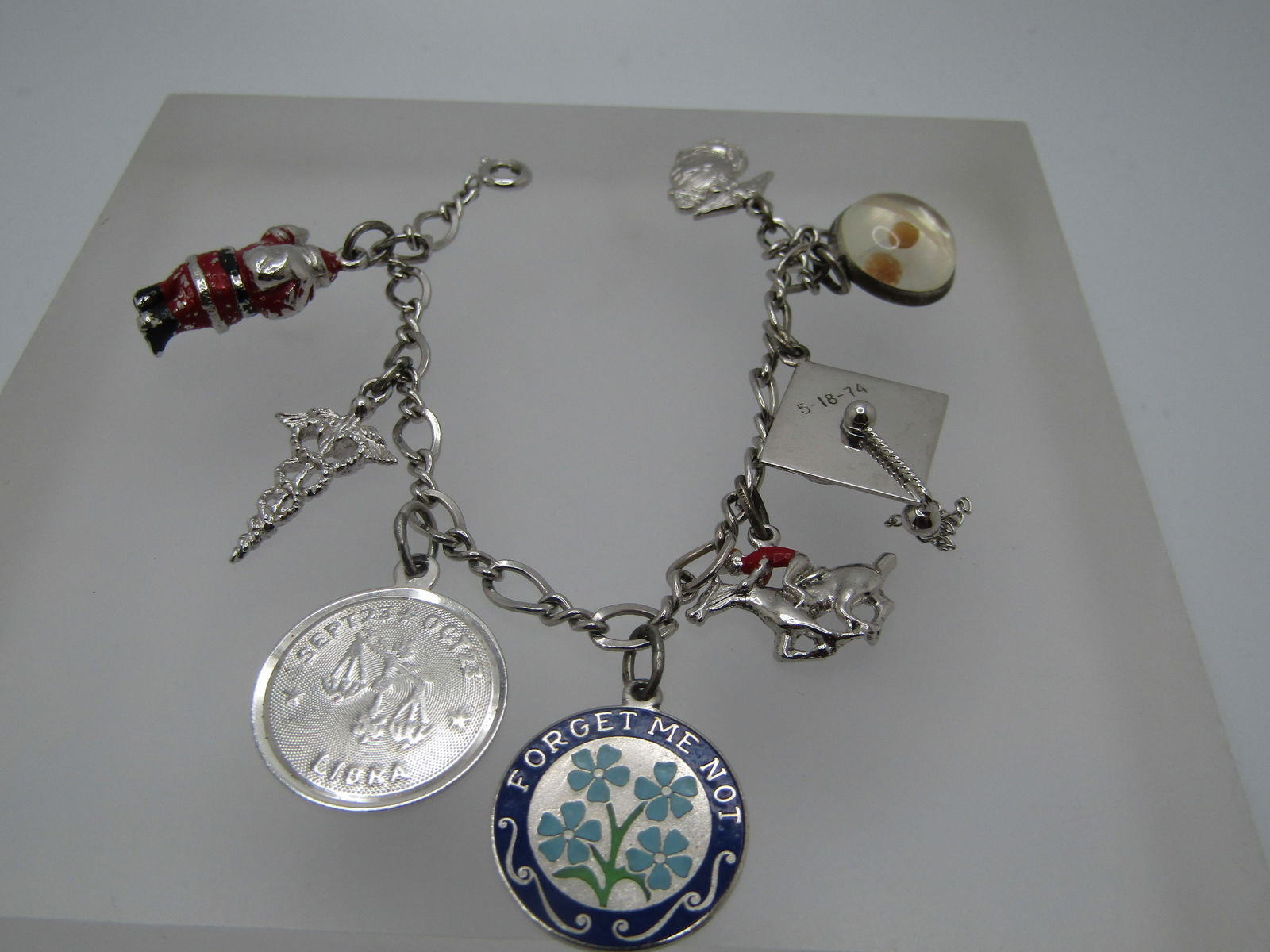 Vintage Sterling Charm Bracelet , 8 Charms, 6", 1970's: Vintage Sterling Charm Bracelet , 8 Charms, 6", 1970's,. The charms are a 3-D enameled Santa , Medical symbol, Libra charm, Enameled Forget-me-Not, enameled horse/jockey, graduation cap from 5/18/74,