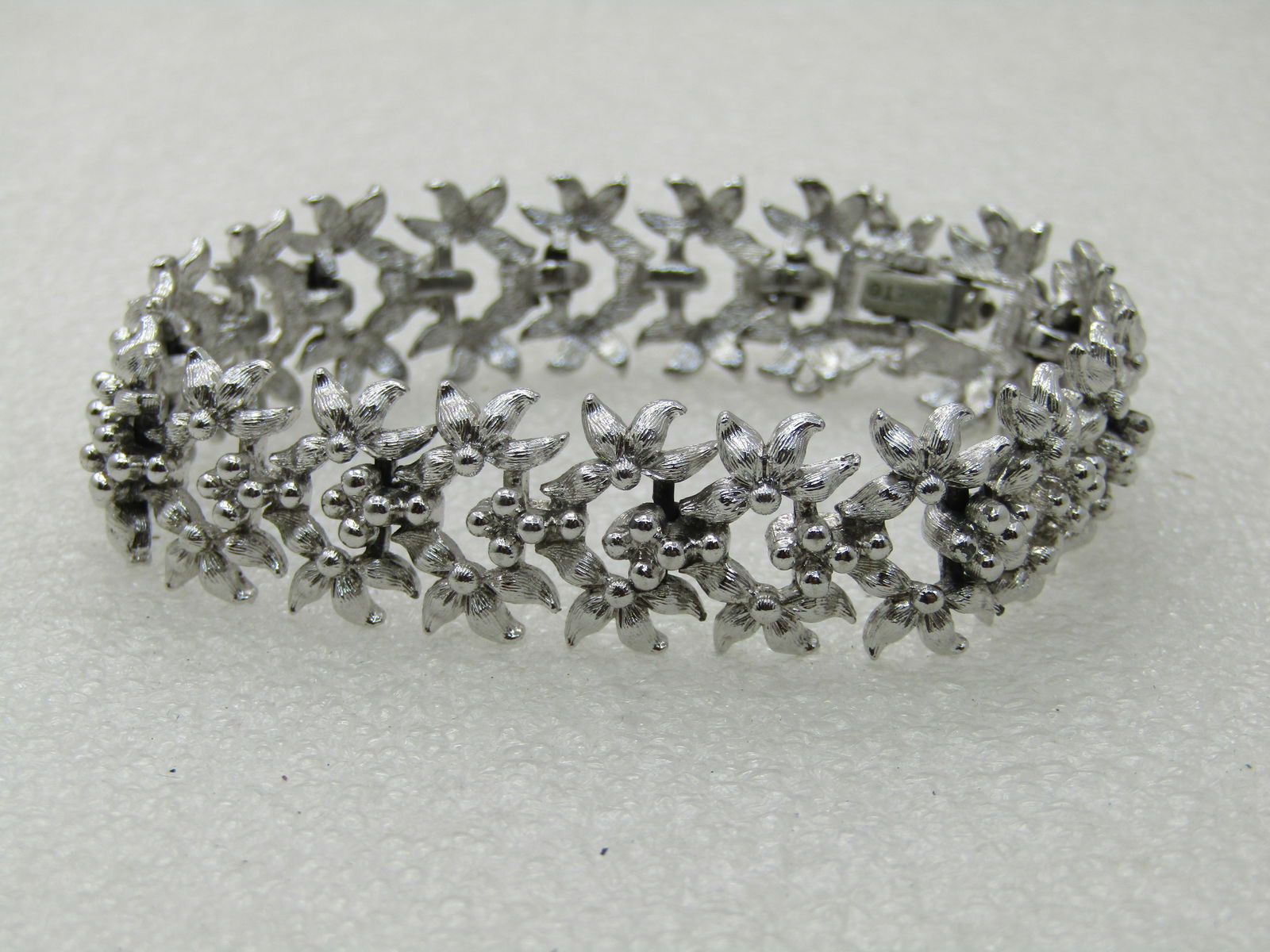 Vintage Monet Floral Bracelet, 7.5", 5/8" Wide, 1960's: Vintage Monet Floral Bracelet, 7.5", 5/8" Wide, 1960's, silver tone,with petite blossoms in three rows - sort of like forget-me-not blossoms. Good condition to very good condition. Very light wear on