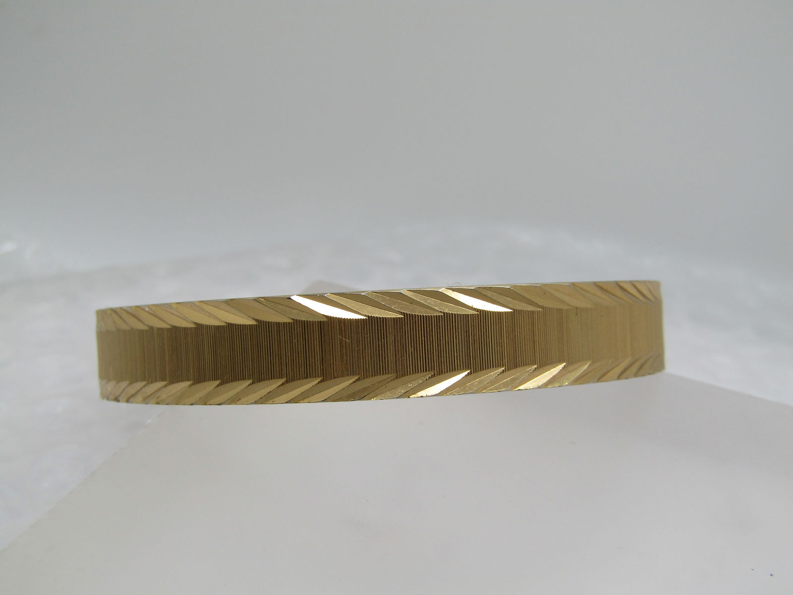 Vintage Monet Diamond Cut Bangle Bracelet, 7.75", 1970's: Vintage Monet Diamond Cut Bangle Bracelet, 7.75", 1970's. Gold tone and 10mm wide. The opening is slightly wider than 2.5". Textured ridged center with angled diamond cut accents on the edges. 