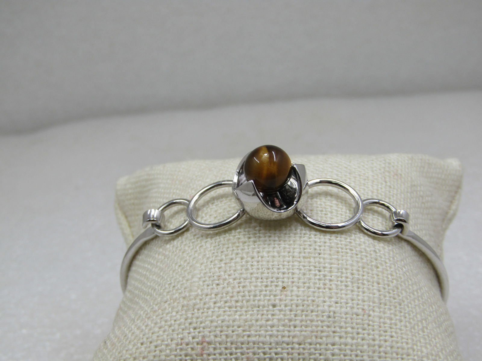 Sterling Silver Tiger's Eye Bangle Bracelet, 7", Top Clasp: Sterling Silver Tiger's Eye Bangle Bracelet, Top Clasp, 7". This has four open rings on top with a center raised claw-like bezel holding a 7mm tiger's eye round stone. The band around the wrist is a