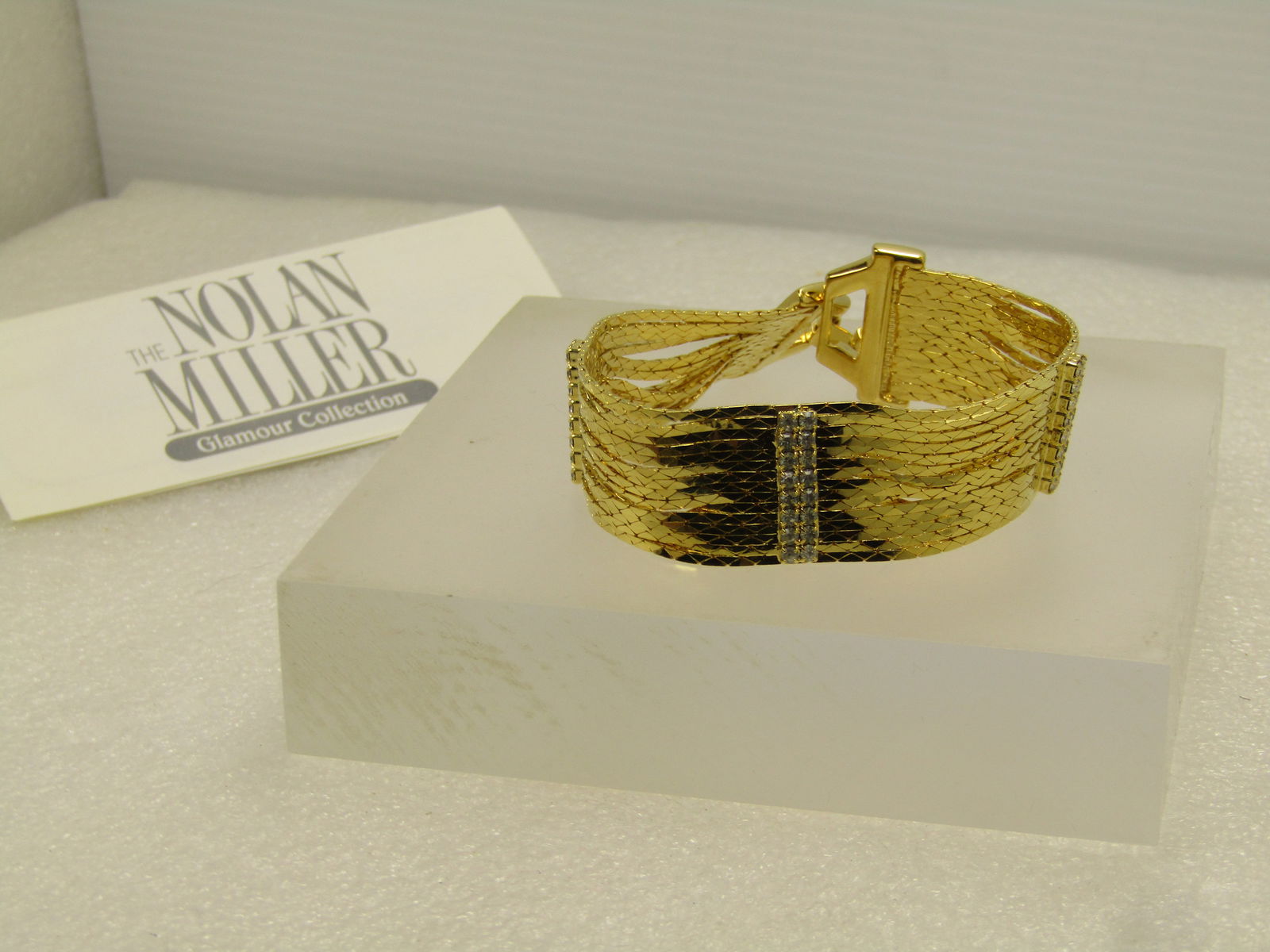 Nolan Miller Glamour Collection 14 Strand Bracelet with Rhinestone Accents, 7.5" in Box: Vintage Gold Tone Multi-Strand Wide Bracelet, Nolan Miller Glamour Collection with Certificate of Authenticity. It is 7.5" wide. It is about 7/8" wide - it has pave rhinestone end pieces with double