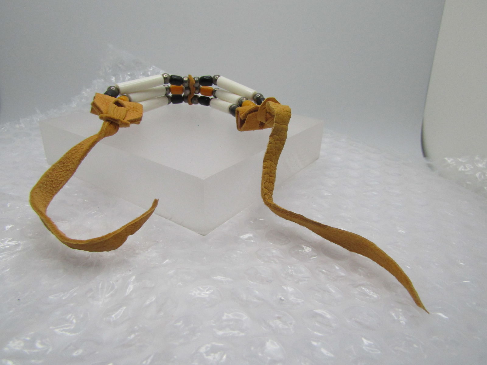 Plastic & Glass Beaded Warrior Bracelet, Leather, Ties, 16" 1980's-1990's: Plastic & Glass Beaded Warrior Bracelet, Leather, Ties, 16" 1980's-1990's. This has three strands with lng white rounded tube beads that are plstic and on each side of those beads there are black