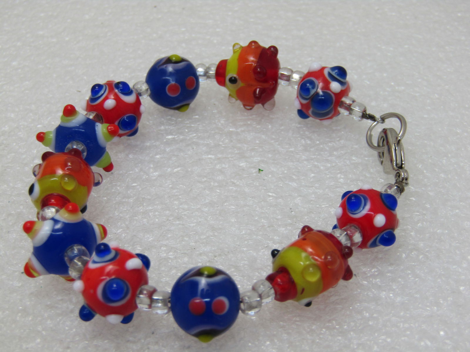 Glass Lampwork Beaded Bracelet, Colorful 8": Glass Lampwork Beaded Bracelet, Colorful 8" and 9mm to 14mm bads with little bumps in multi-colors, red, orange, blue, yellow, white and black. Lobster clasp. (INV. W.UNK 3720.5 SS1311 LEB LD 5/9/20)