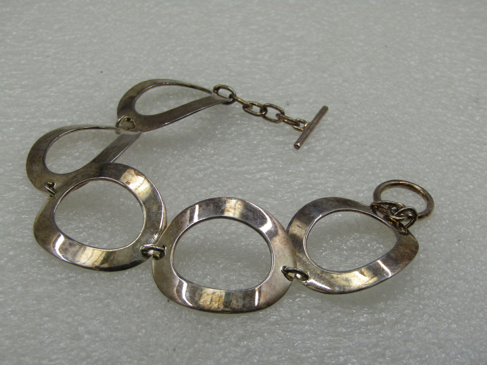 Silver Hammered Wide Oval Linked Bracelet, 7.5", Toggle Clasp: Silver Hammered Wide Oval Linked Bracelet, 7.5", Toggle Clasp 1" wide. This is marked .925 and has the look of sterling however it may either not be sterling or plated as it does not test strongly