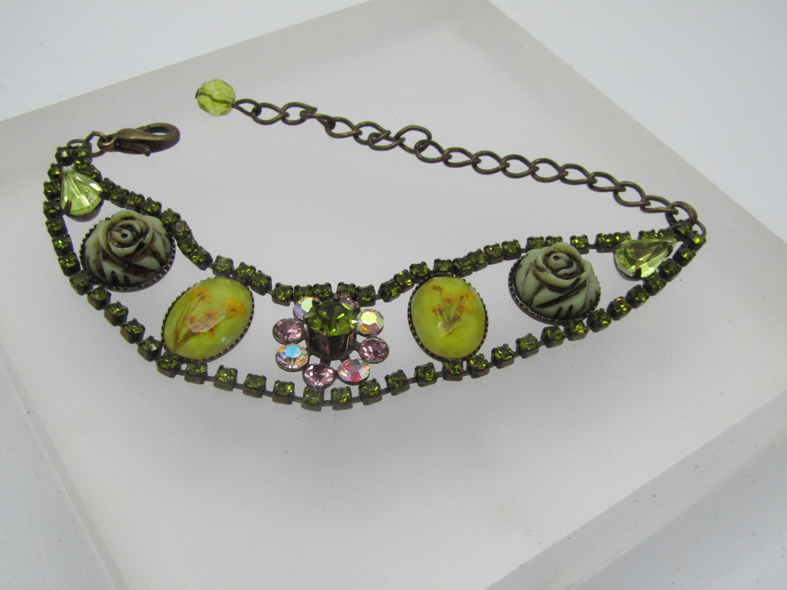 Vintage Rhinestone & Floral Accented Bracelet, 6"-9": Vintage Rhinestone & Floral Accented Bracelet, 6"-9". this has a row of green rhienstones set on each end that is appx. 2.5mm wide. In between it has open area with a tapered design that is 3/4" at ce