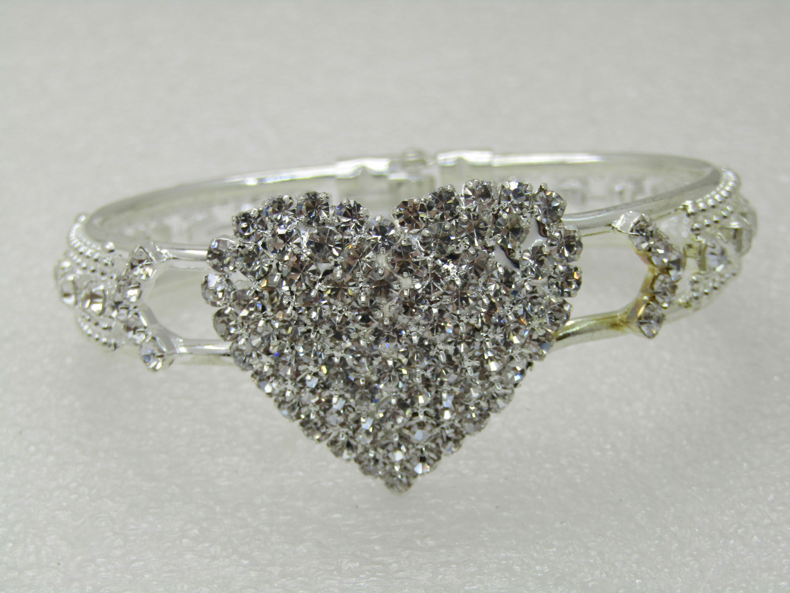 Rhinestone Heart Clamper Bracelet, 6.75", Silver Tone, Pave-Set: Rhinestone Heart Clamper Bracelet, 6.75", Silver Tone, Pave-Set, Top Opening of 2.5" from side-to-side and 2" front-topback. 1-1/8" heart that opens in the center to slip on your wrist with a silver