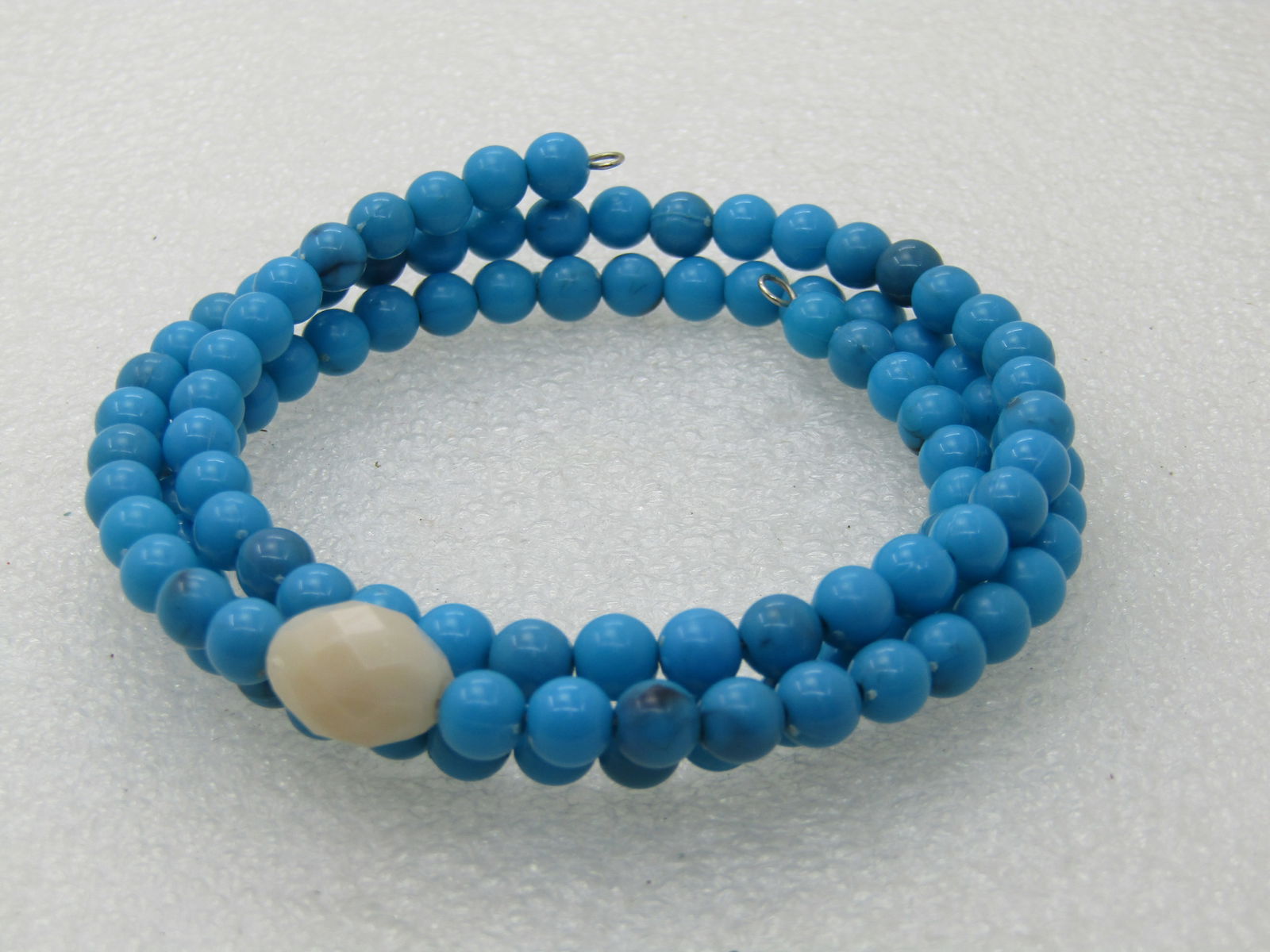 Vintage Turquoise Blue & White Beaded Coiled Bracelet, 7.75": Vintage Turquoise Blue & White Beaded Coiled Bracelet, 7.75" with three coilds of plastic turuqoise 5.5mm round beads and a single white faceted bead that is oval and appx. 12mm long and 9mm wide.