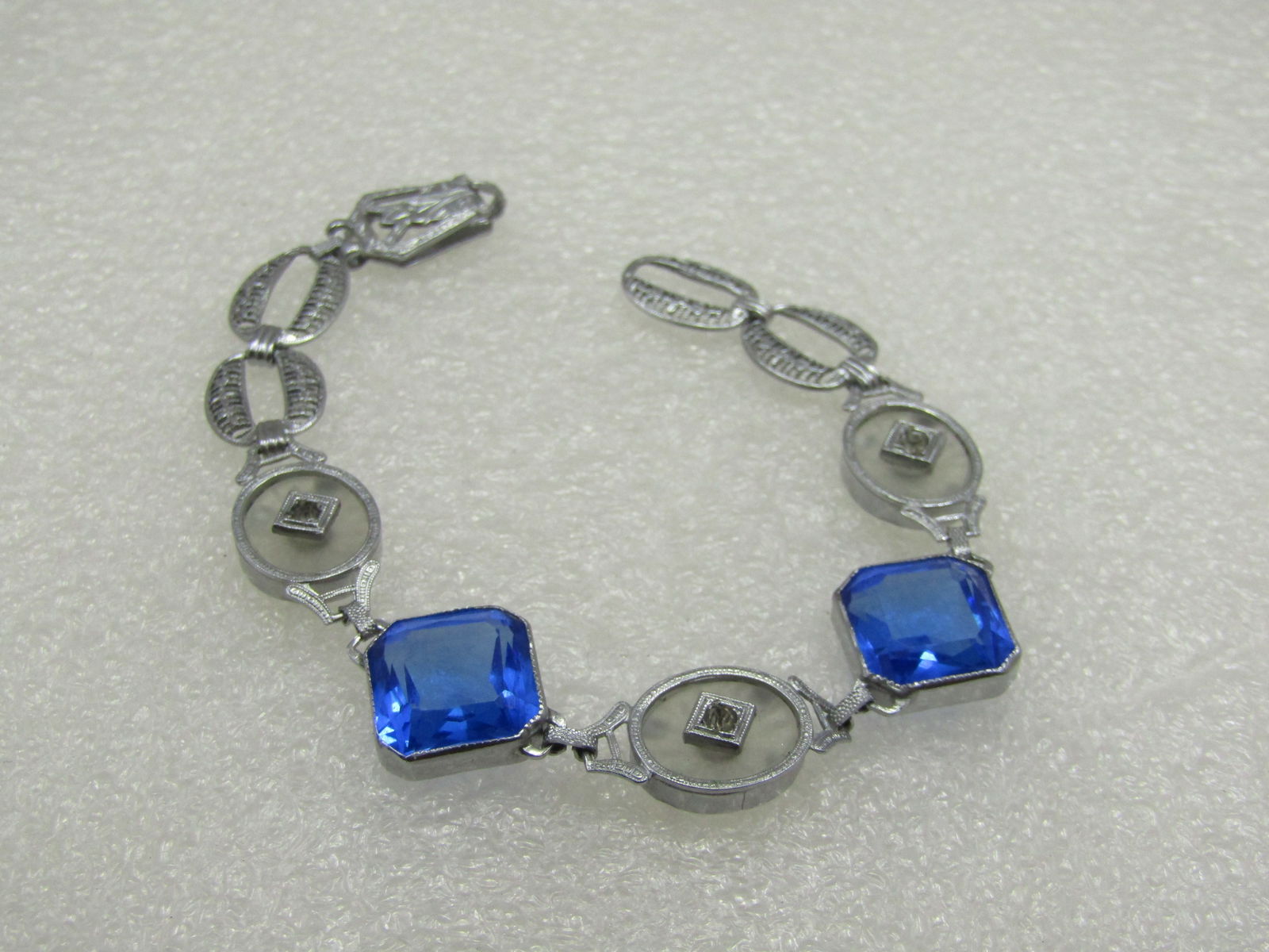 Rhodium Plated Camphor & Glass Art Deco Bracelet, 7": Rhodium Plated Camphor & Glass Art Deco Bracelet, 7". This is appx. 15mm wide at the square blue glass faceted bezel-set stones that are appx. 13.5mm long down each side with angled corners. There
