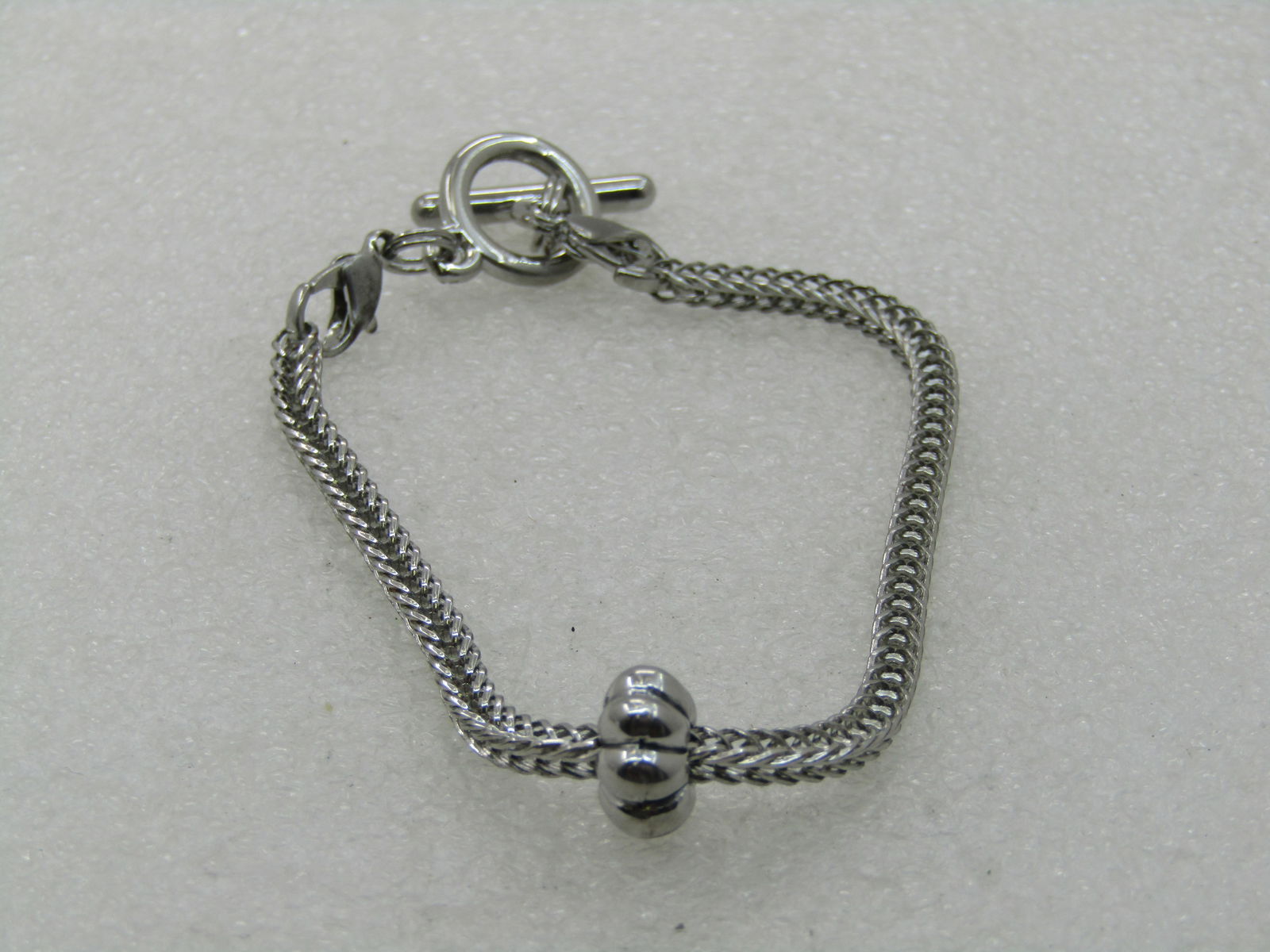 Vintage Wheat Link Toggle Bracelet, 7.5" Silver Tone: Vintage Wheat Link Toggle Bracelet, 7.5" Silver Tone. Age is appx. 1990's. It has a squared wheat link chain that is appx. 2.7mm wide with a fluted slide bead. Toggle clasp. Each clasp end is attached