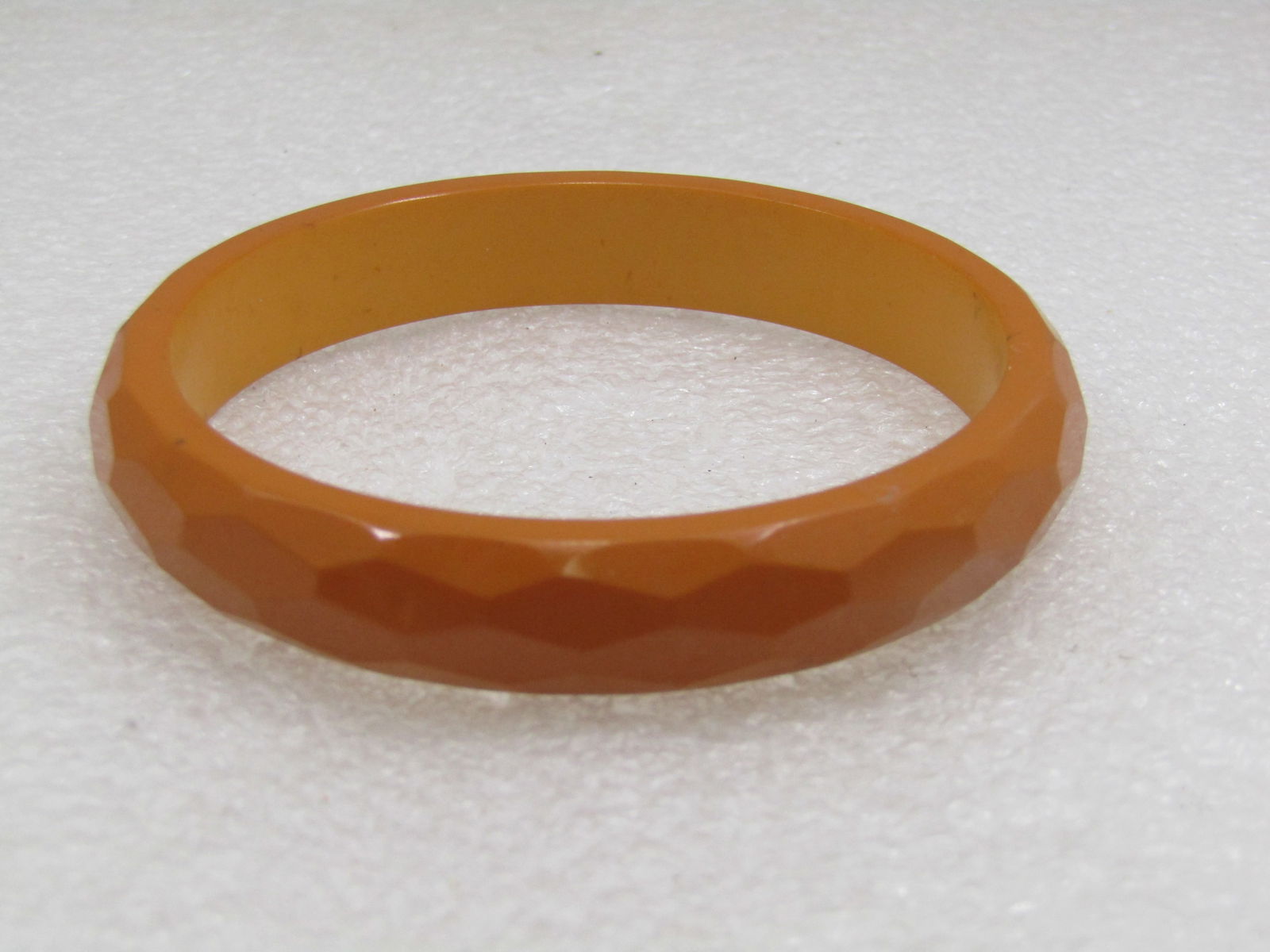 Vintage Tan Faceted Plastic Bangle Bracelet. 7.75": Vintage Tan Faceted Plastic Bangle Bracelet. 7.75". Round with a domed outer edge that has facets around the bracelet. It is 1/2" wide and the opening is 2.5" across. It is slightly ligher on the