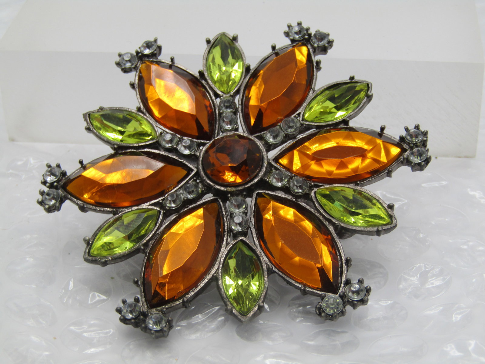 Vintage Green/Amber RS Clip, 3" Blossom: Vintage Green/Amber RS Clip, 3" Blossom design with marquise luciTe amber and peridot colored strones with clear rhinestones throughout. A round amber stone in the center. Textured silver tone pewter