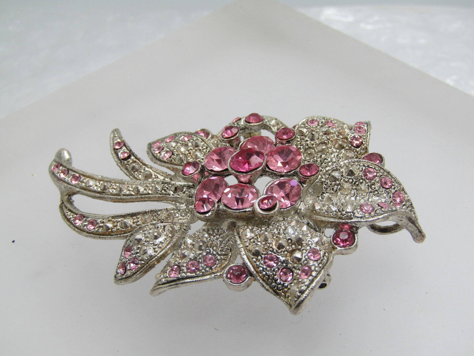 Pink Rhinestone Faux Marcasite Floral Brooch, 2.75": Pink Rhinestone Faux Marcasite Floral Brooch, 2.75" by 2". A cluster of mixed sized round cut pink stones, some lighter/some darker in the center and smaller ones scattered around the brooch with faux