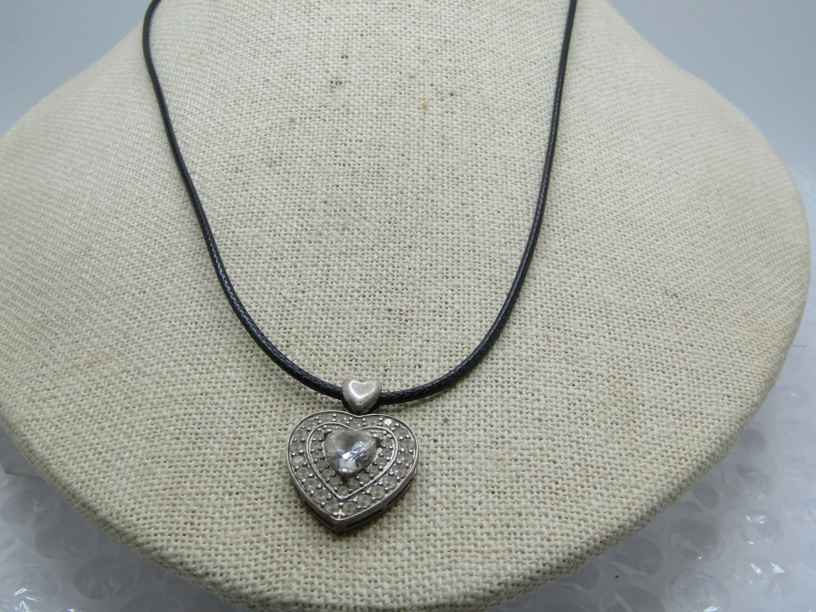 Vintage Sterling Heart Moissanite Necklcae, 20" Black Cord Chain, Signed CW: Vintage Sterling Heart Moissanite Necklcae, 20" Black Cord Chain, Signed CW. The pendant has a heart bail from which a heart shaped pendant drops with a heart moissanite stone set on top. The stones