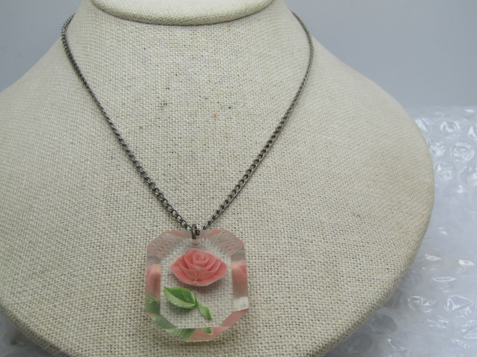 Vintage Reversed Carved Pink Rose Necklace, 16", 1940's: Vintage Reversed Carved Pink Rose Necklace, 16", 1940's. Carvd angled clear lucite pendant with a pink rose and green leaf and stem. The pendant is wider on top, and shorter on the bottom as it is