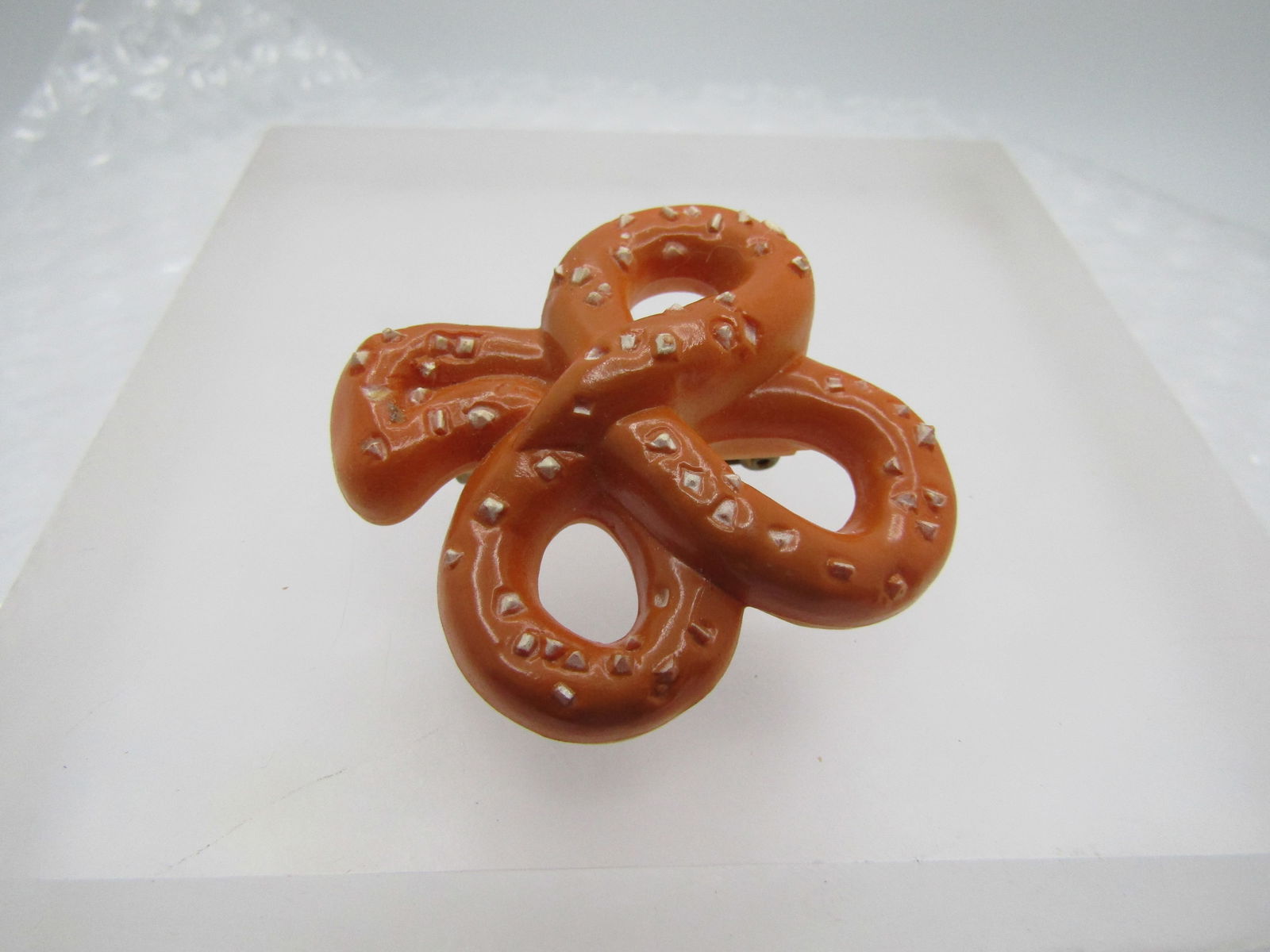 Vintage Pretzel Brooch, 1.75" by 1.5", 1970's: Vintage Pretzel Brooch, 1.75" by 1.5", 1970's. In the shape of a three-leaf clover. Made of a molded plstic that is pretzel brown on top with salt accents. Not signed or marked Very good